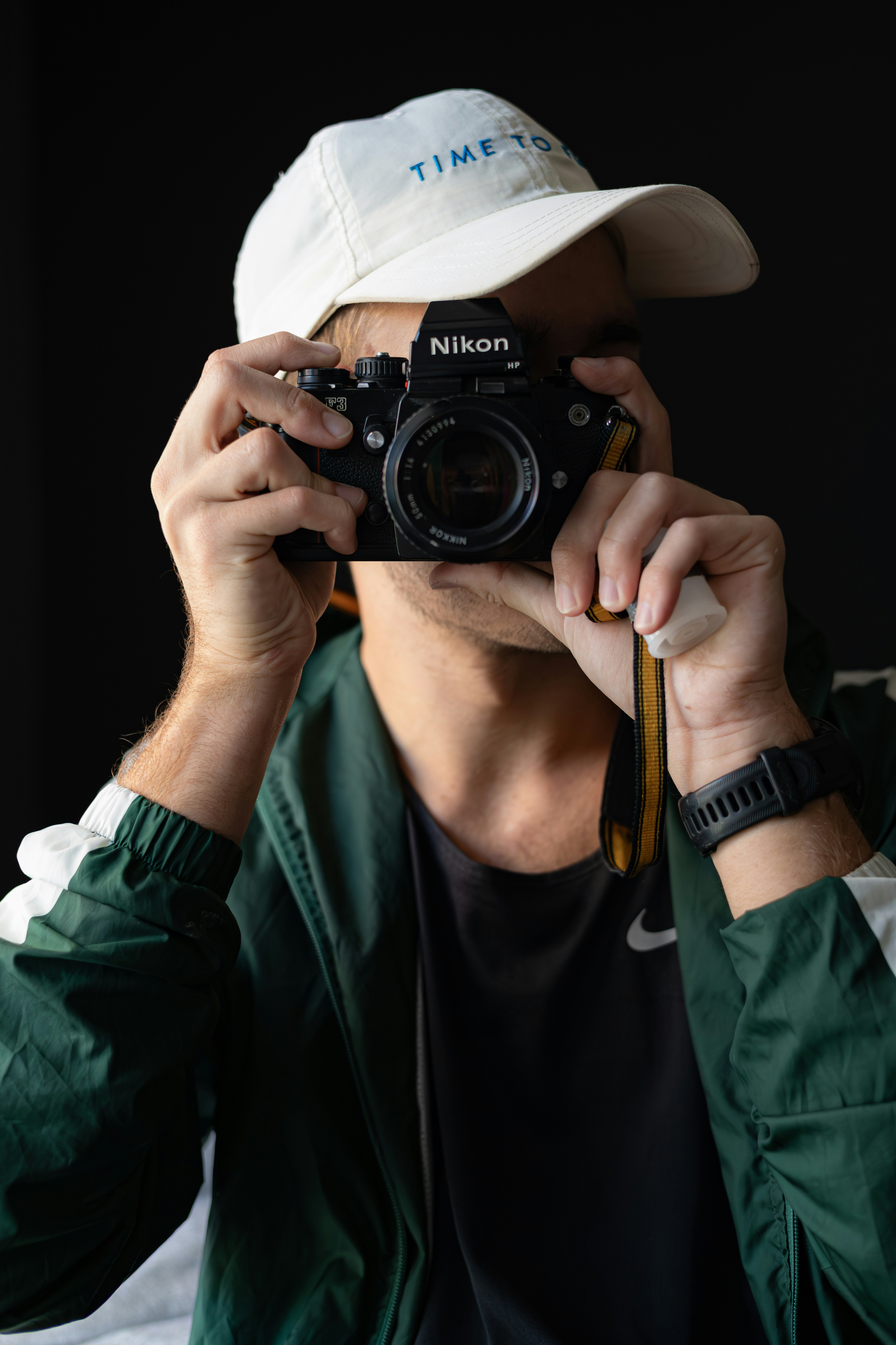 Man wearing a hat and jacket holding a camera