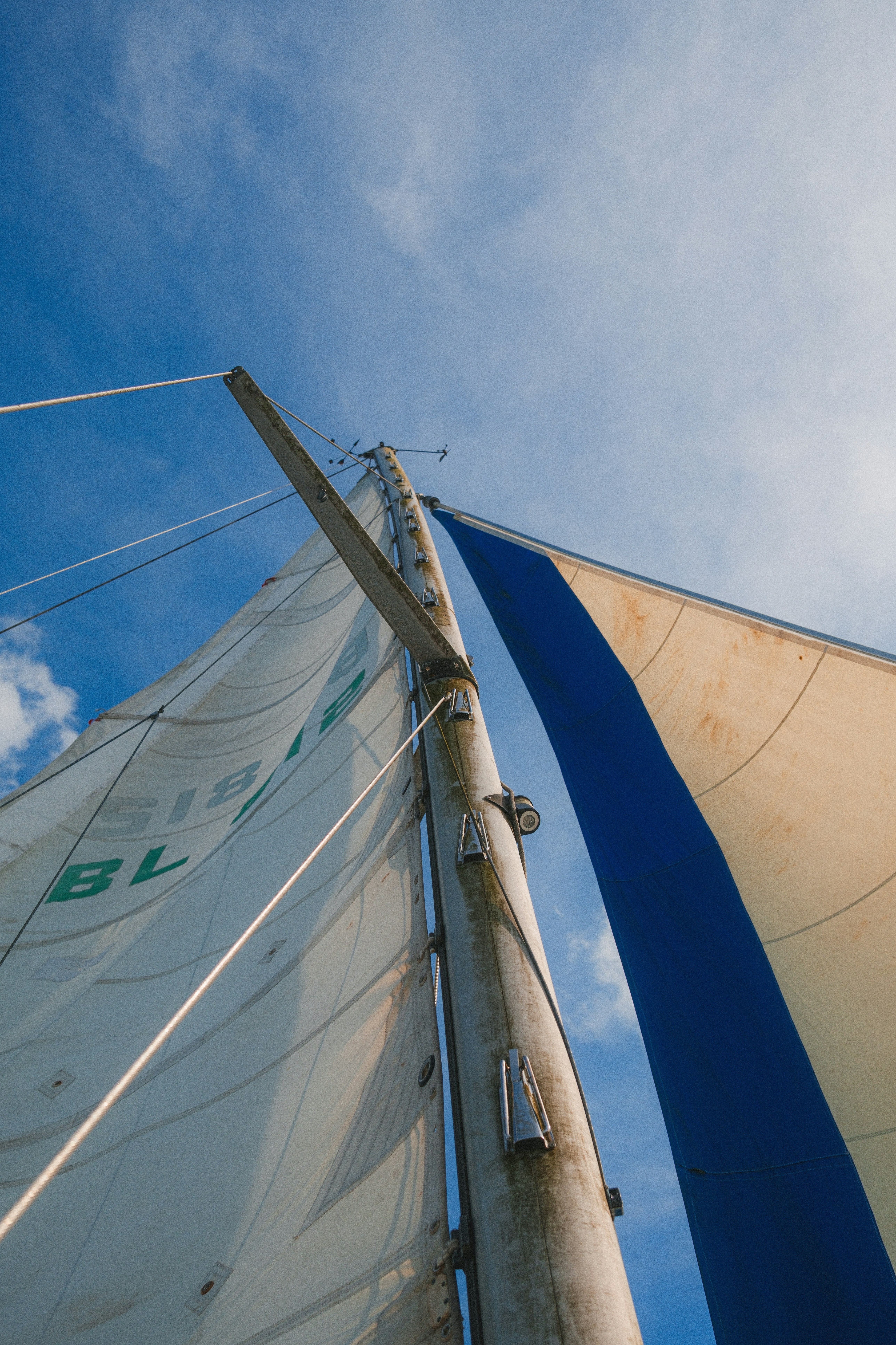 Sailboat mast and sails against a blue sky