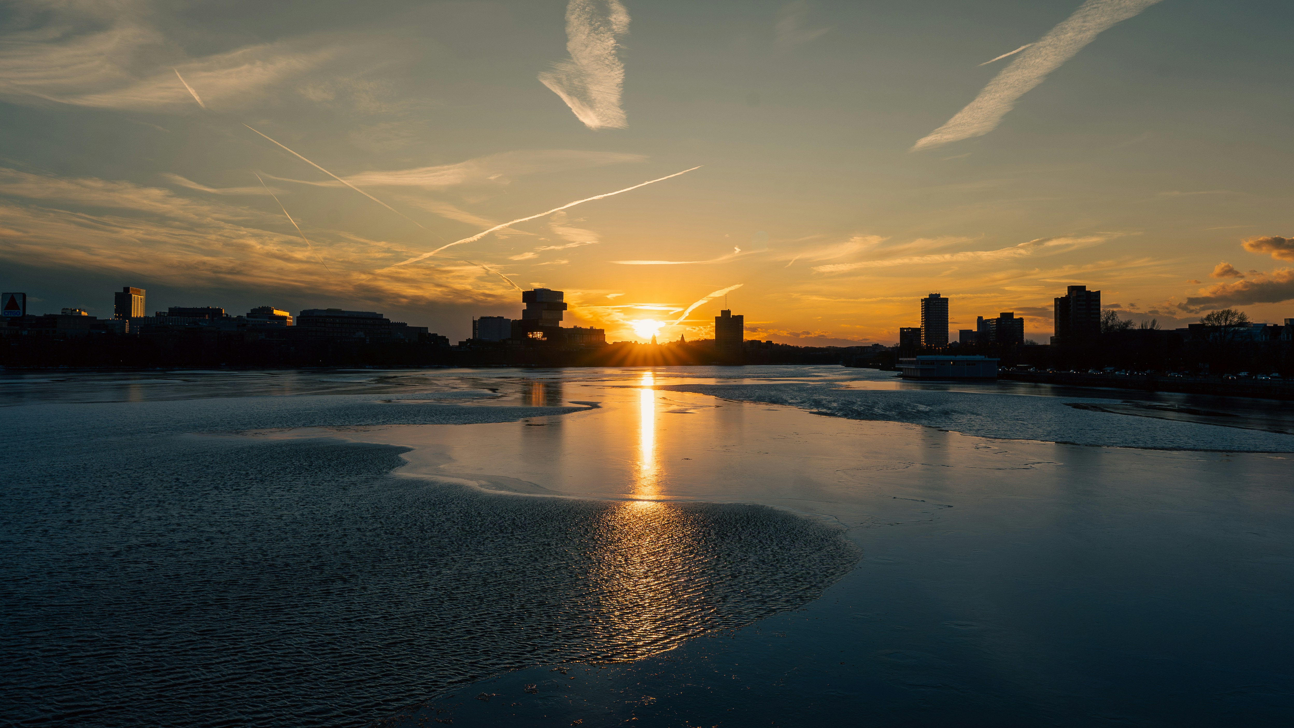 Puesta de sol sobre el horizonte de una ciudad tranquila con reflejos de agua