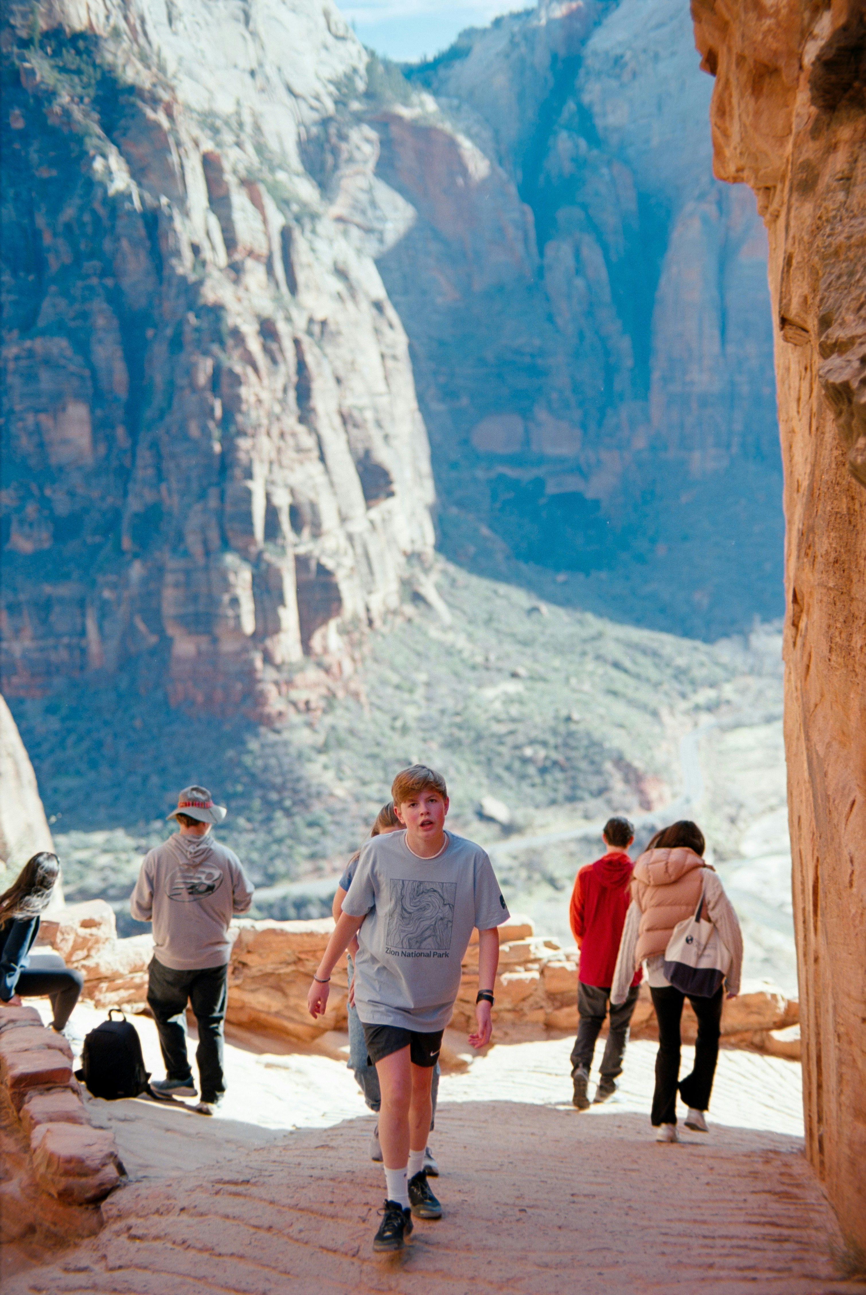 Hikers walk a path through a scenic mountain canyon.