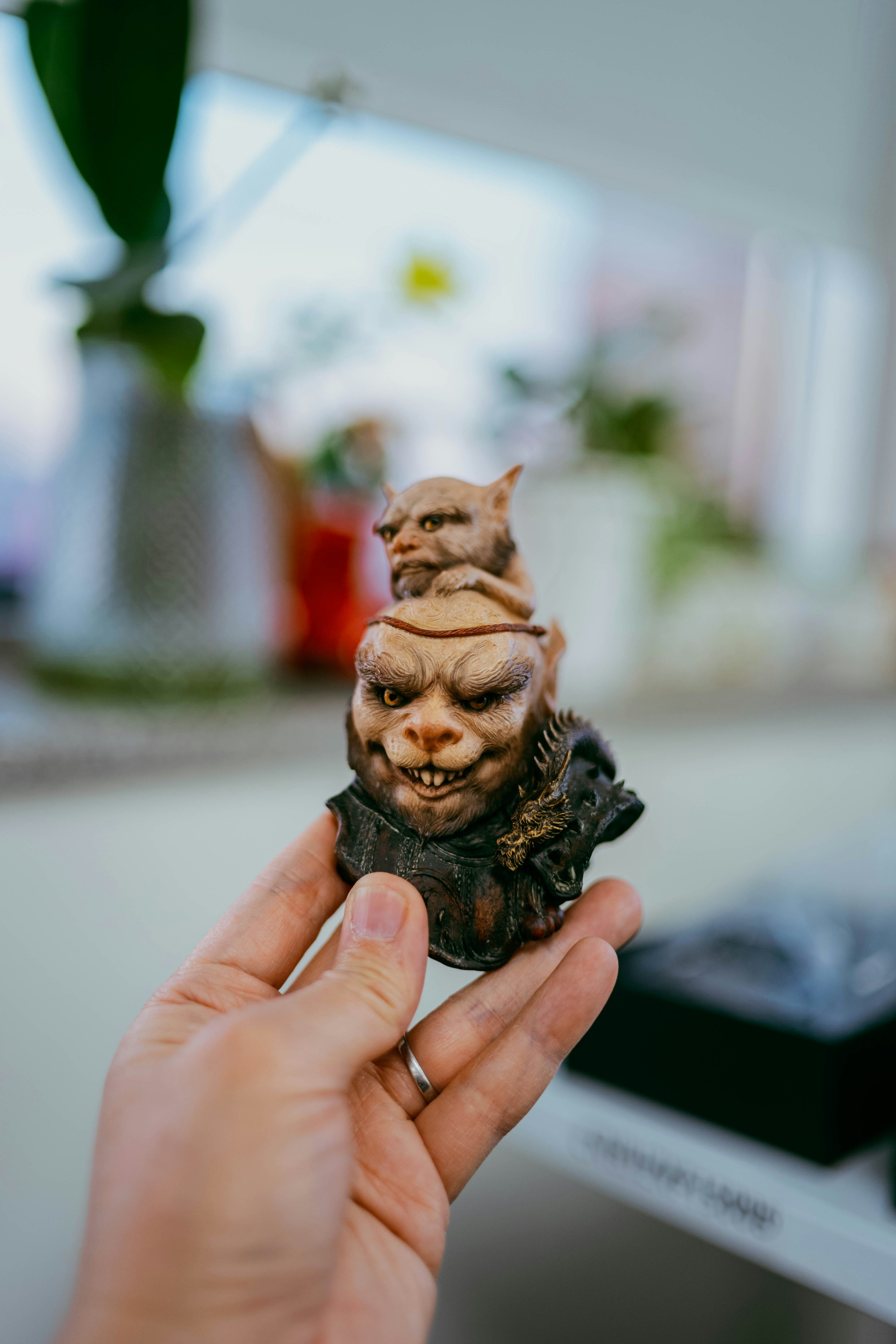 Die Hand hält eine kleine, gruselige Figur mit zwei Gesichtern.