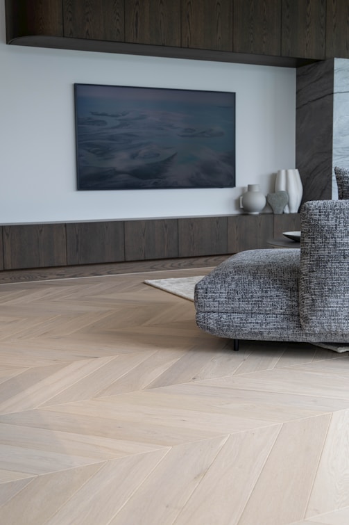 Modern living room with herringbone wood floor and artwork.