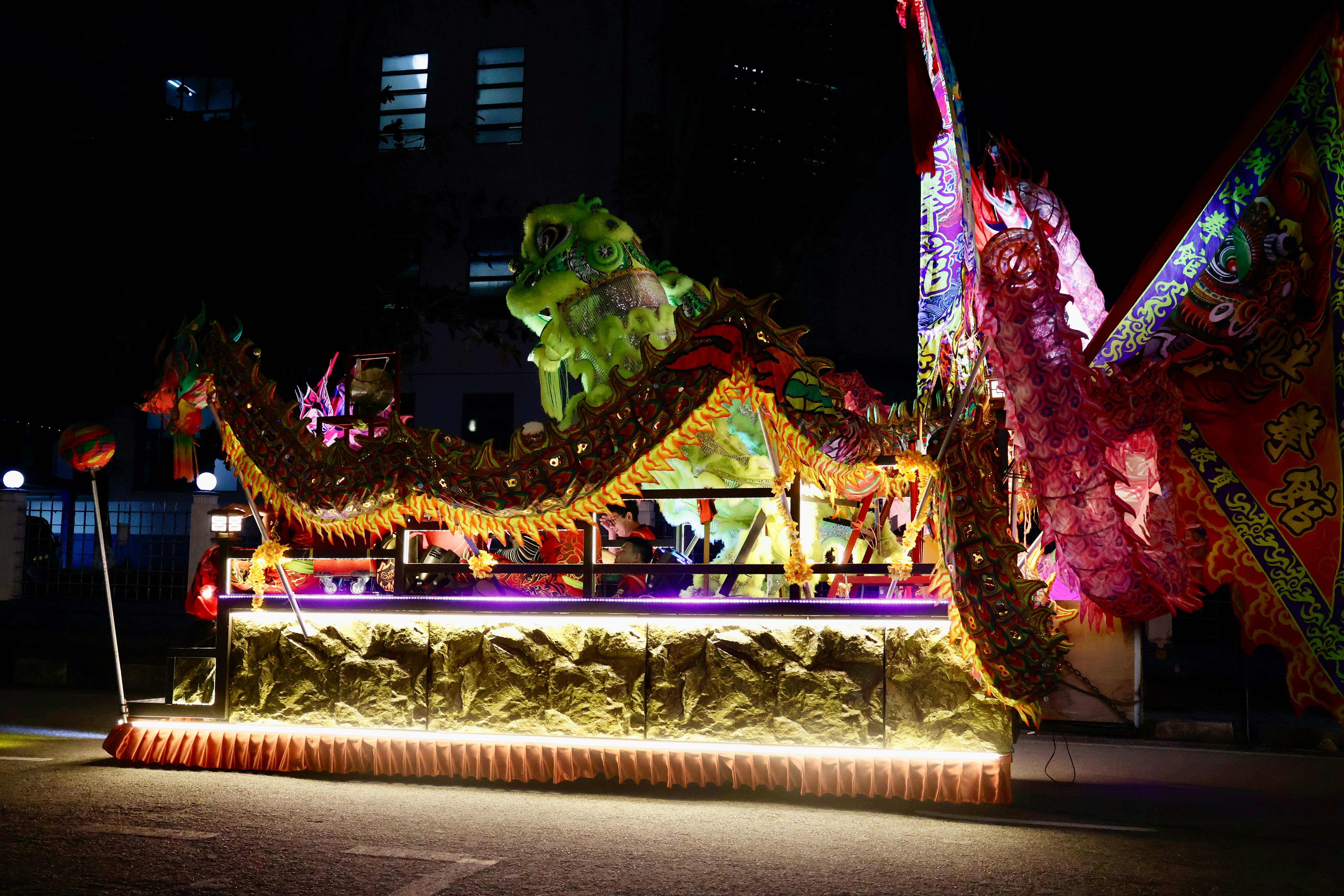 A colorful illuminated parade float at night.