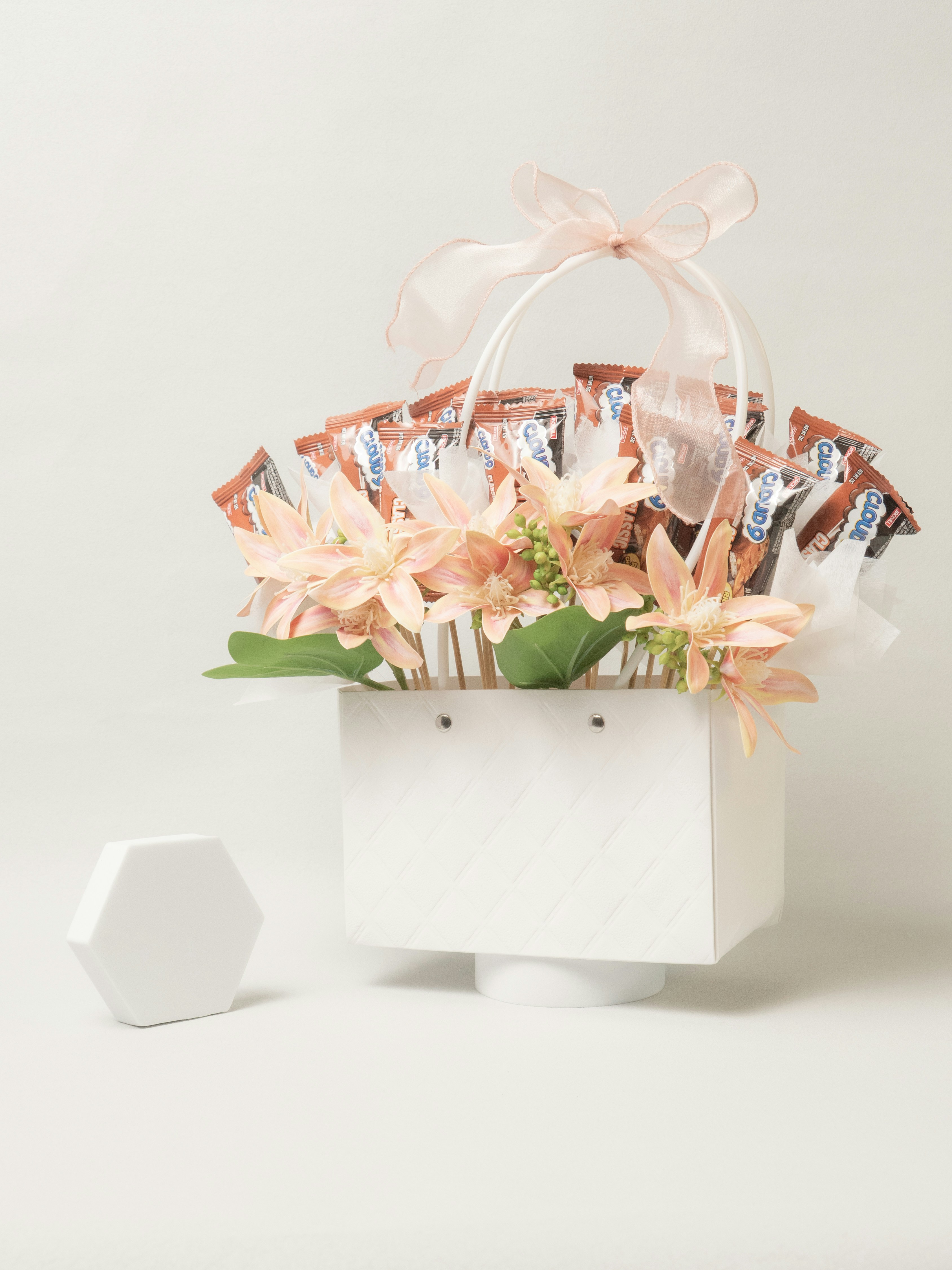 White basket arrangement with candies and artificial flowers