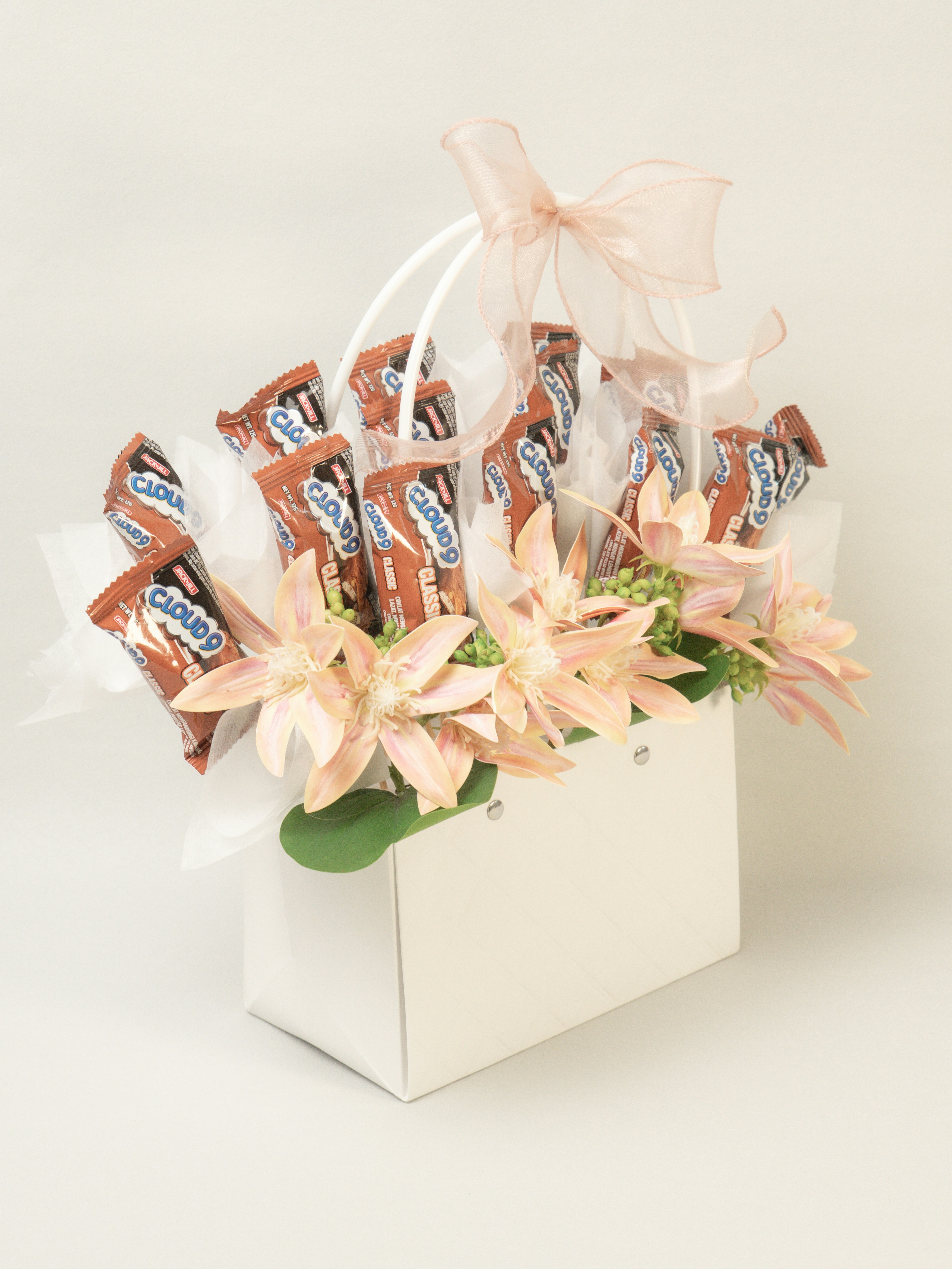 Chocolate bars and flowers arranged in a white bag