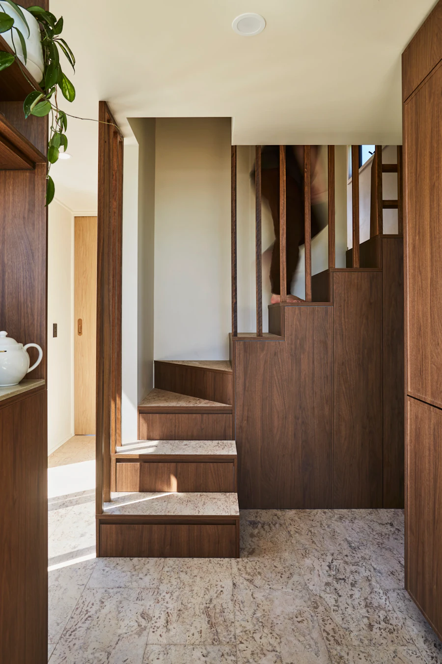 A warm wood staircase with paneled stair sides, integrated storage, and light flooring.