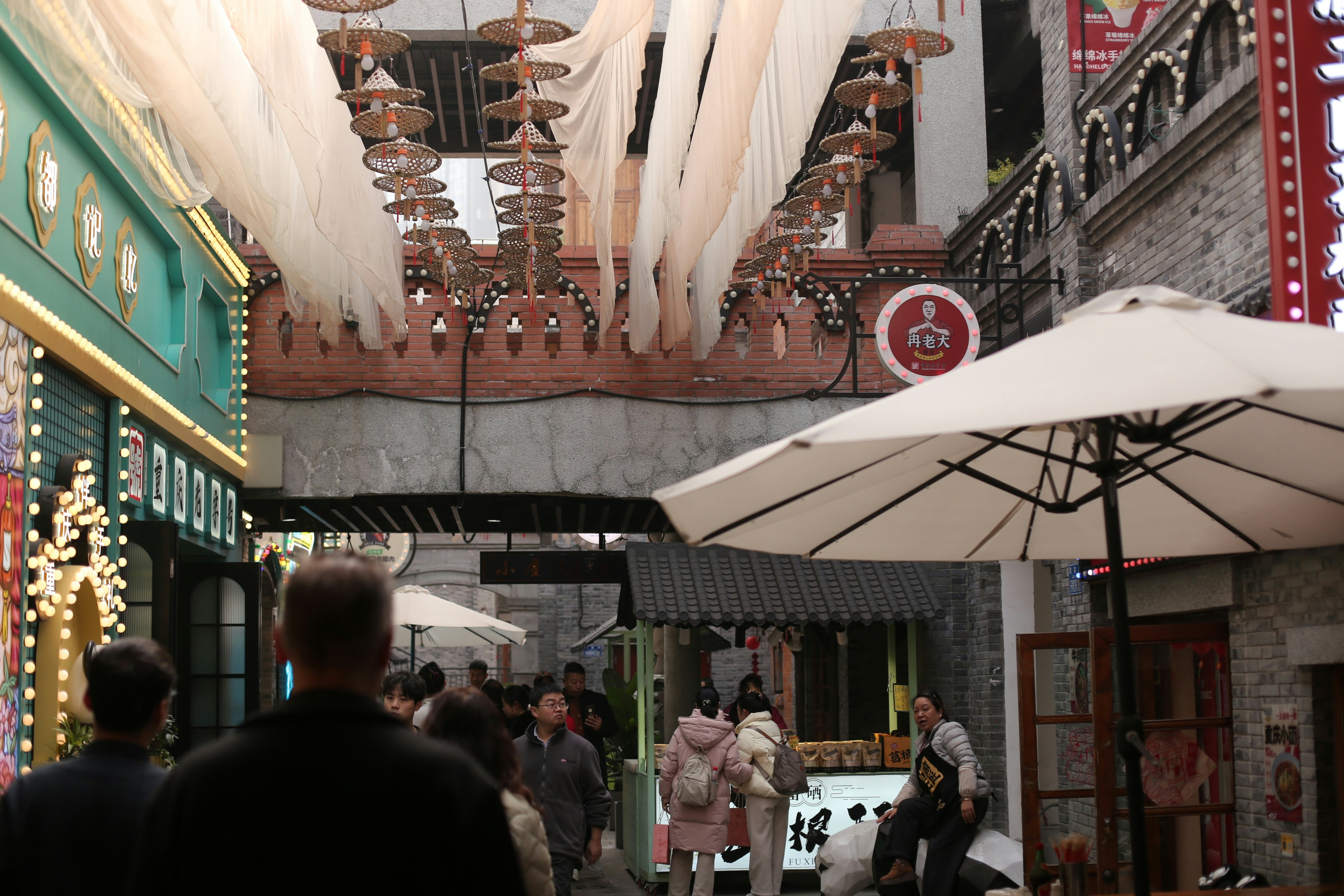 Les gens marchent dans une ruelle étroite avec des boutiques et des décorations.