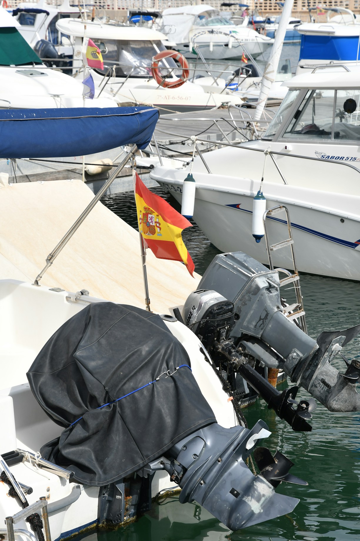 Boats docked in a harbor with spanish flag.