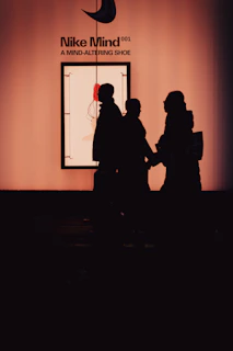 Silhouettes of people in front of nike mind shoe exhibit.