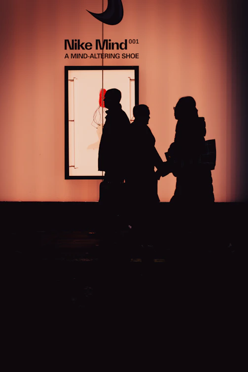 Silhouettes of people in front of nike mind shoe exhibit.