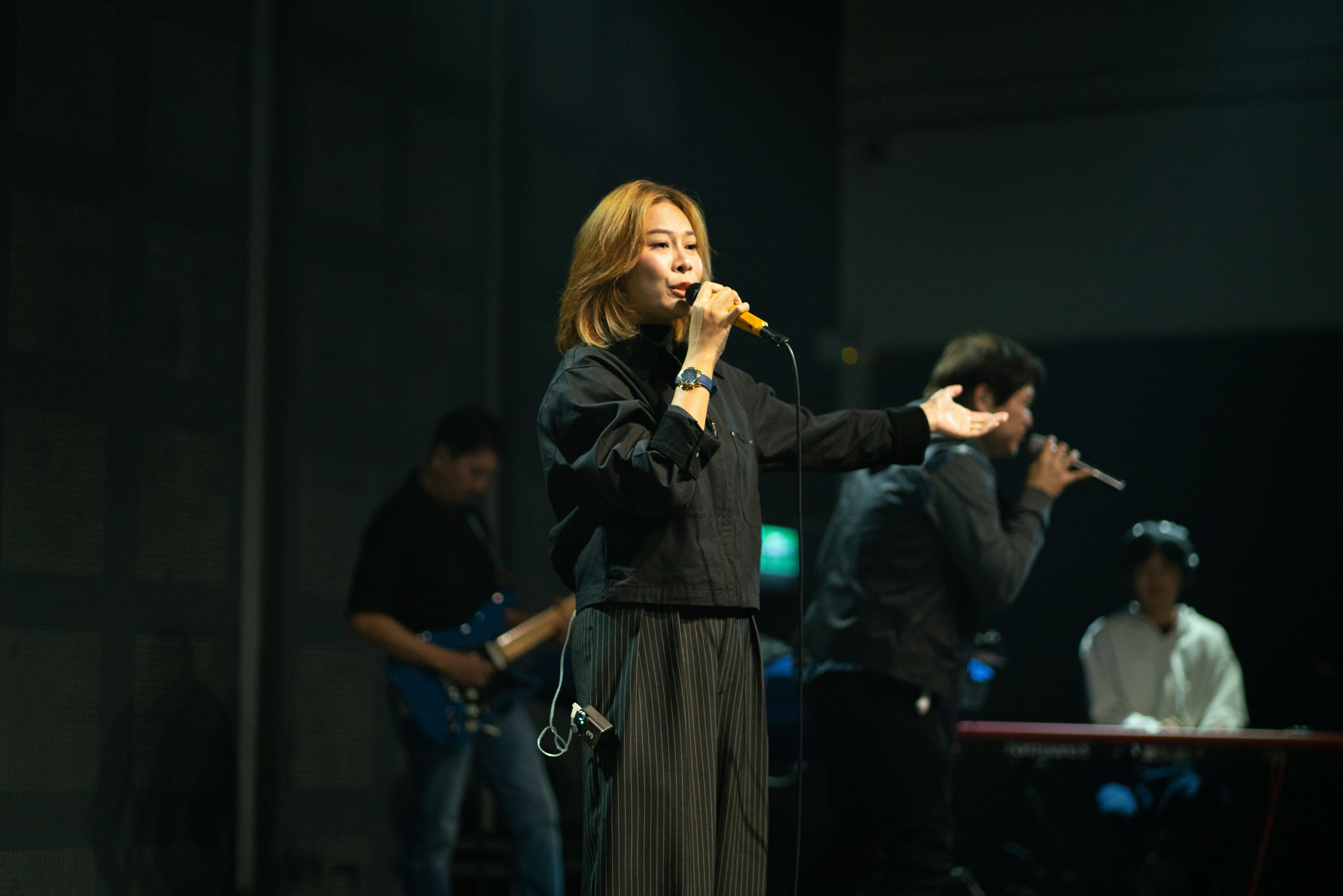 A woman sings into a microphone on stage.