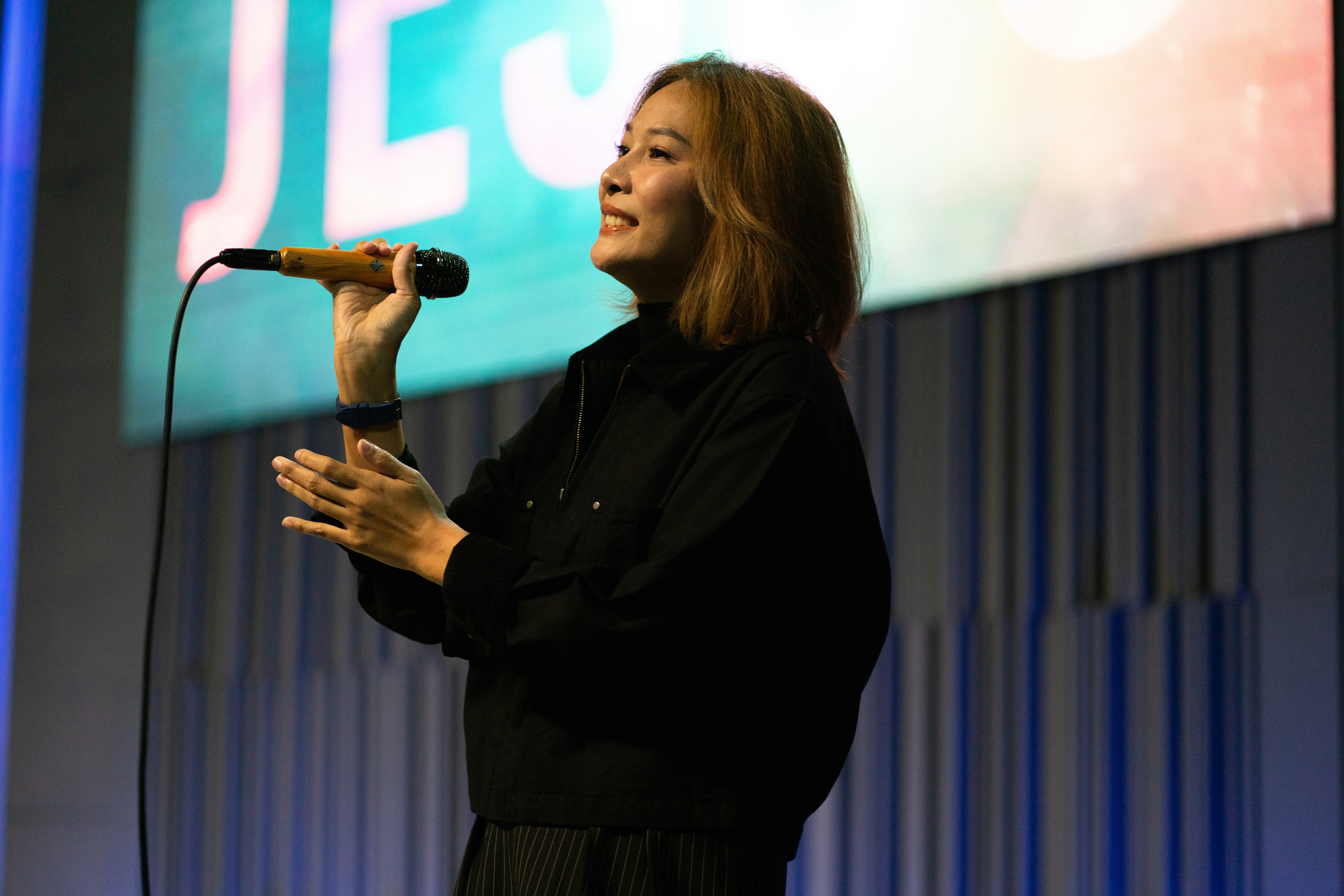A woman sings into a microphone on stage.