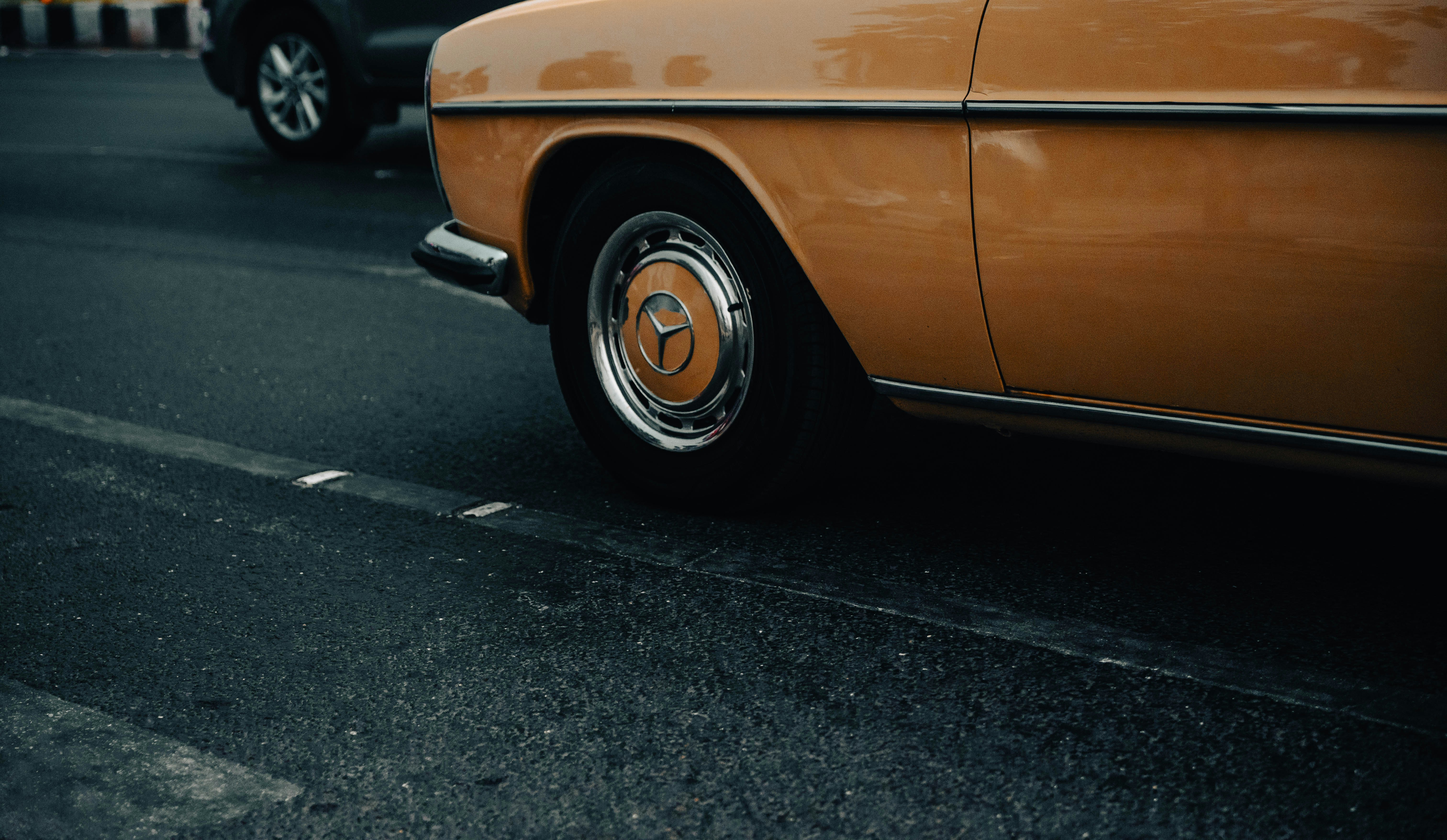Close-up of a vintage orange car wheel on the road.