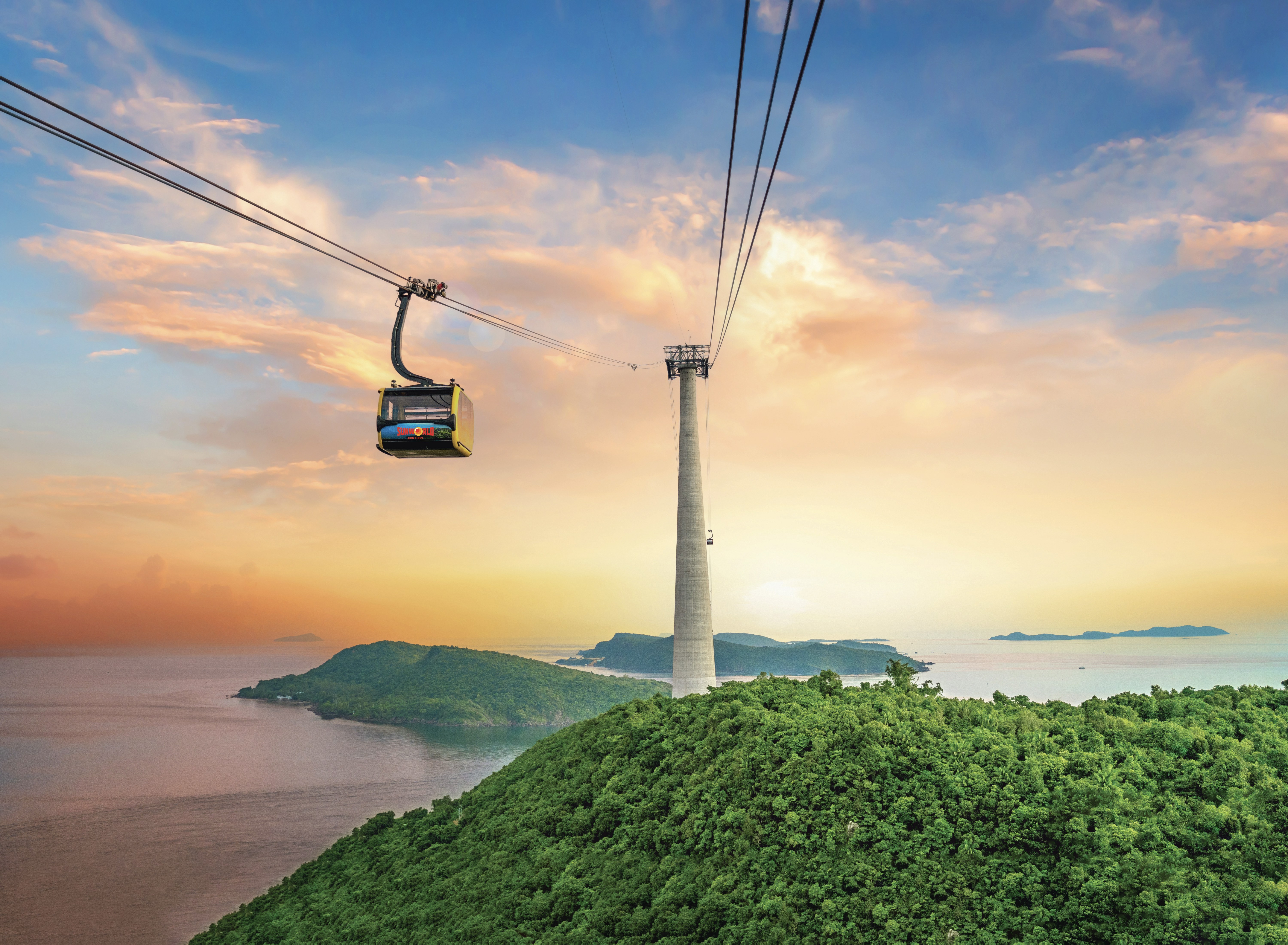 Cable car moving over lush green island at sunset