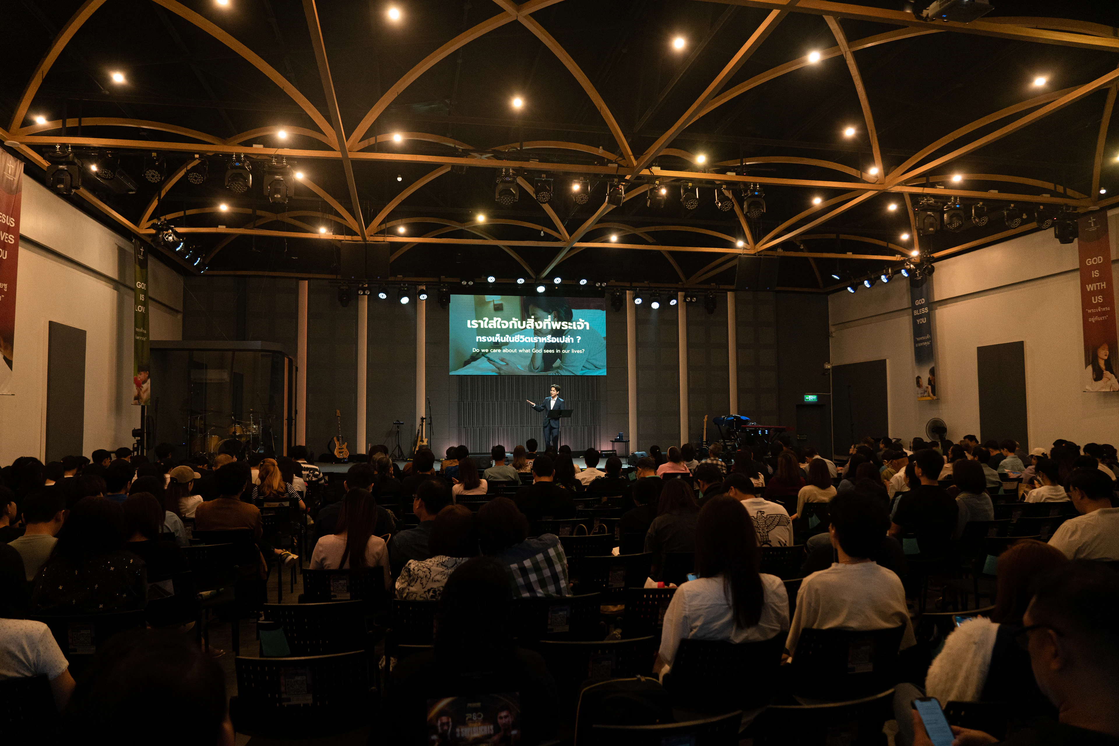 A speaker addressing a large audience in a dimly lit hall