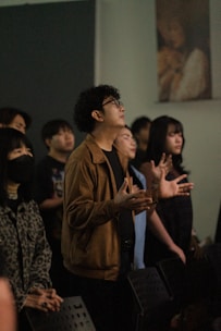 Young adults gathered, looking upwards with hands raised.