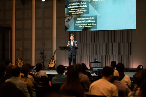Speaker addressing an audience in a modern auditorium.