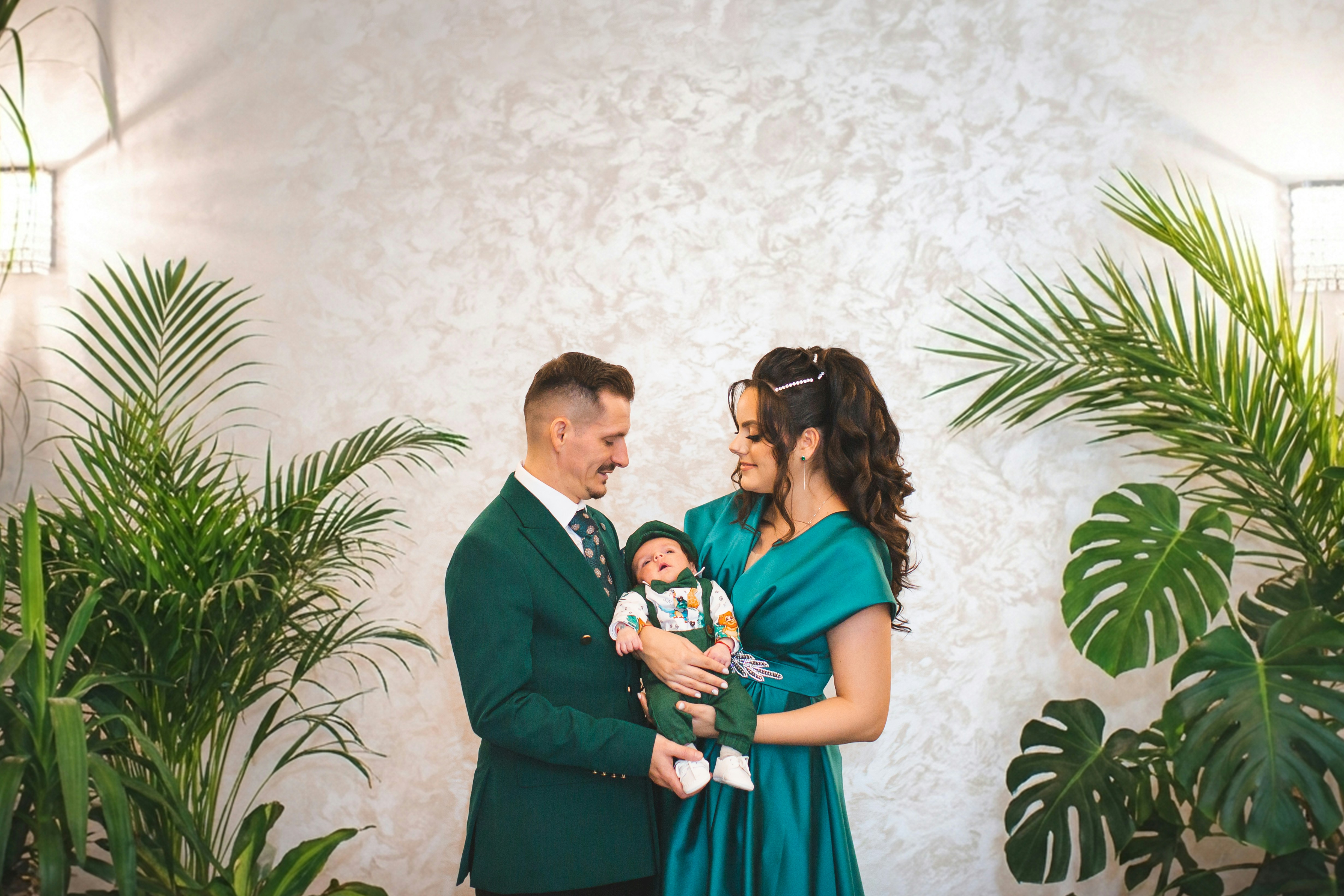 Los padres sostienen a su bebé recién nacido rodeados de plantas