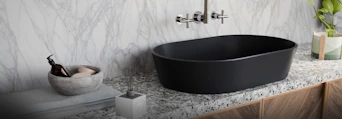 Modern black oval sink with marble wall and countertop.