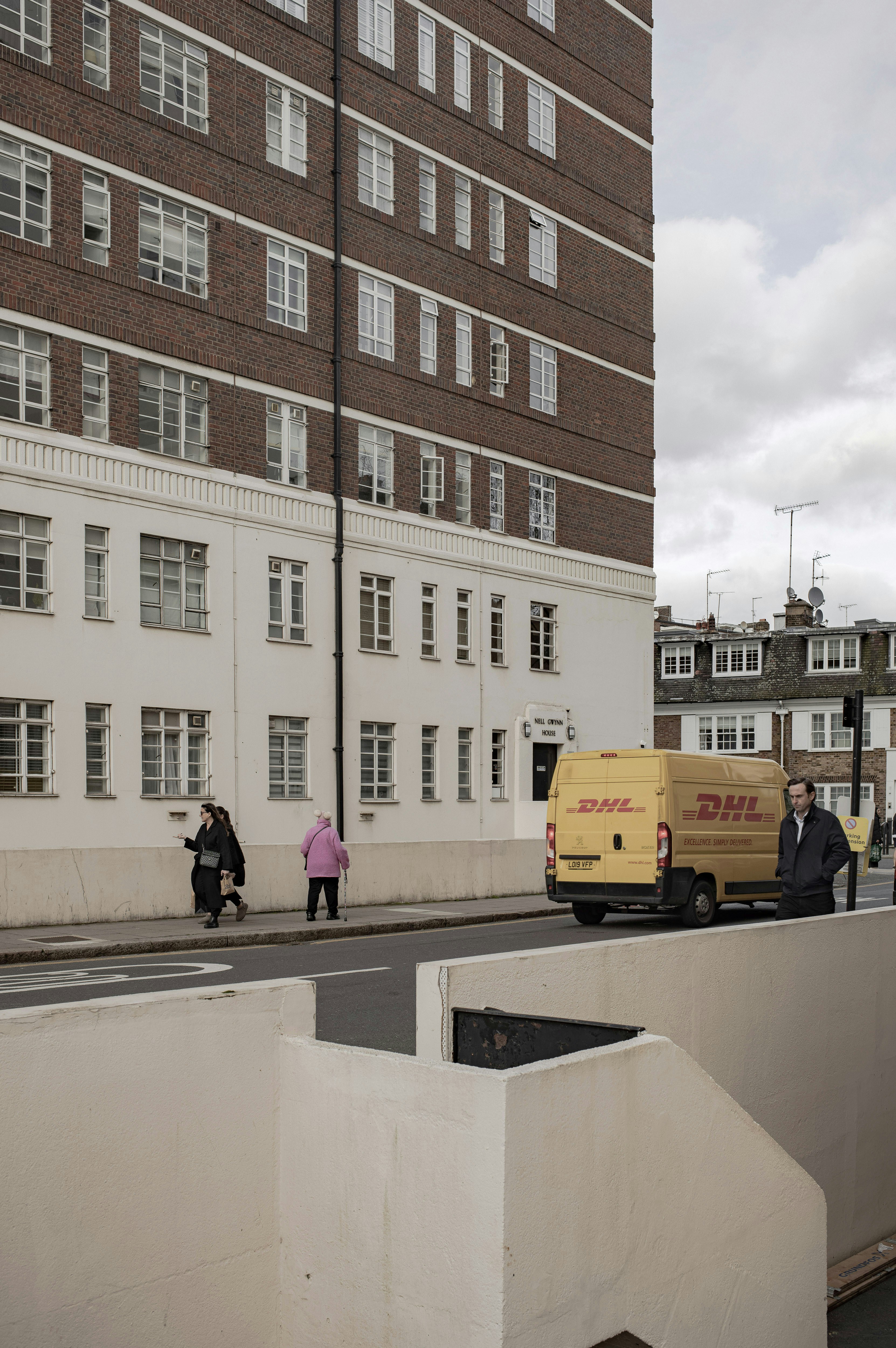 Two dhl vans parked outside a brick building.
