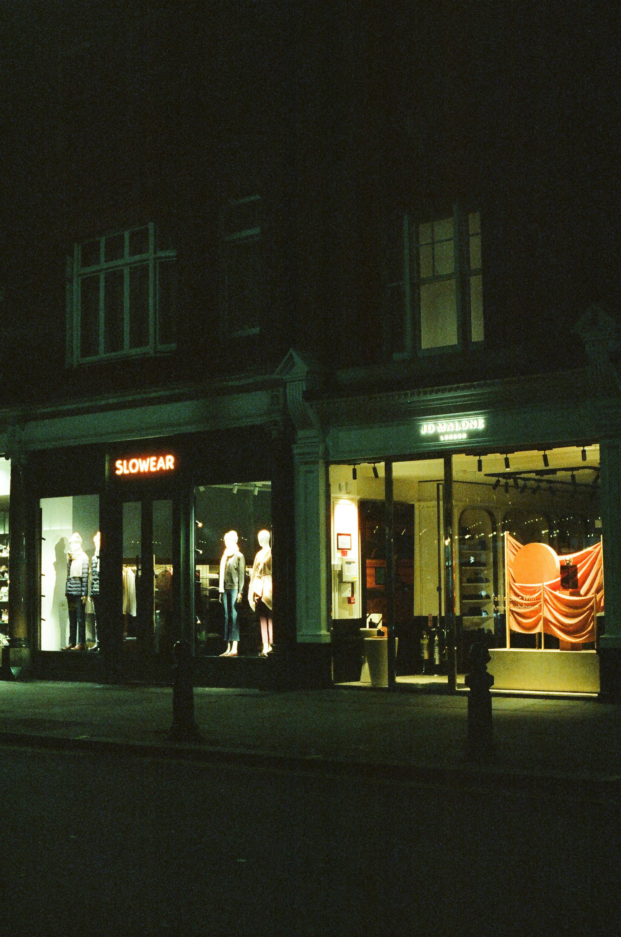 Storefronts illuminated at night with mannequins displayed.