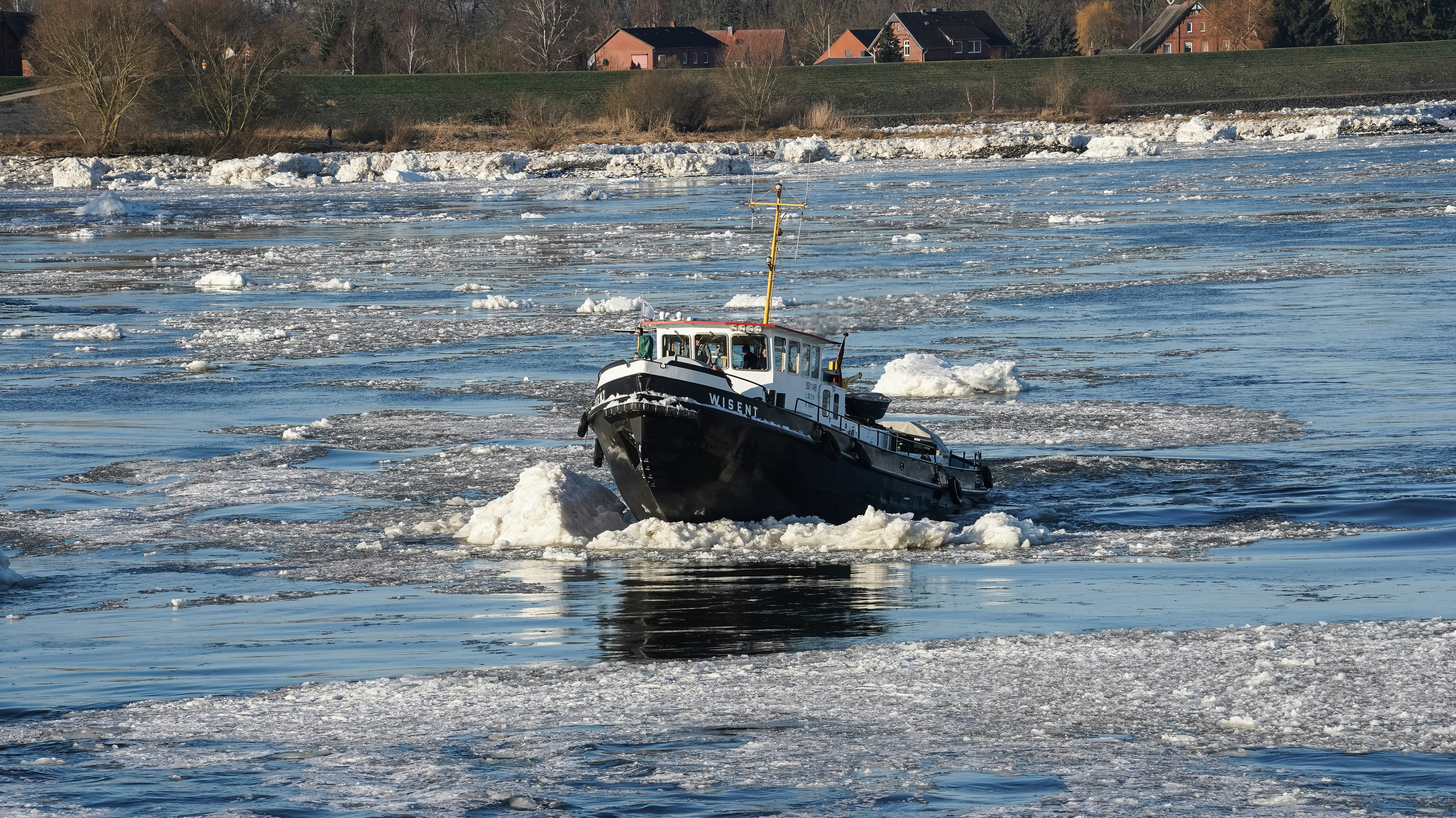A tugboat navigates through icy water