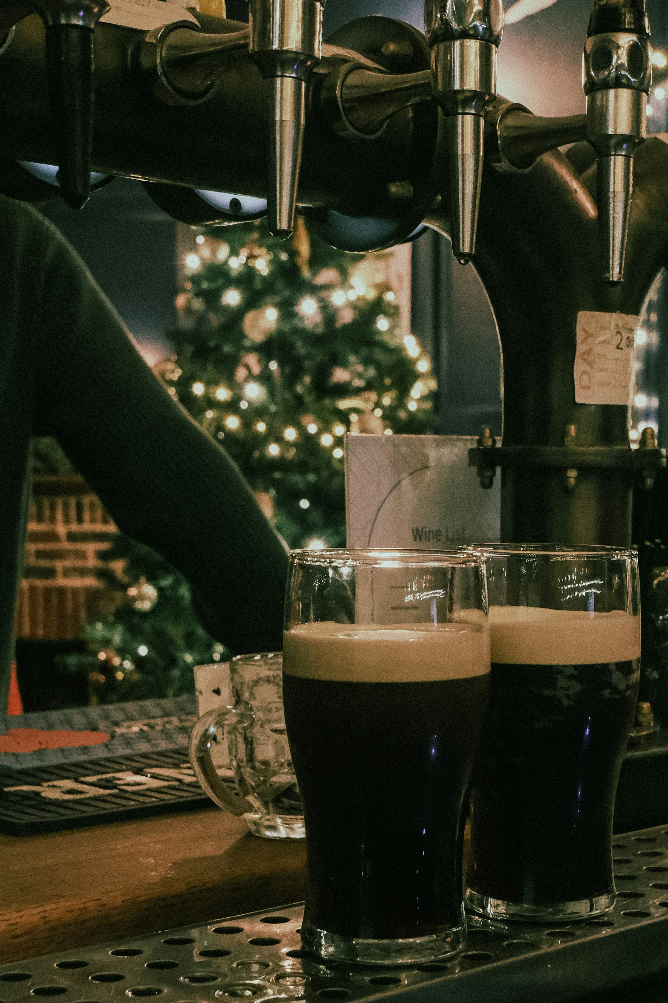 Two dark beers on a bar with christmas tree background