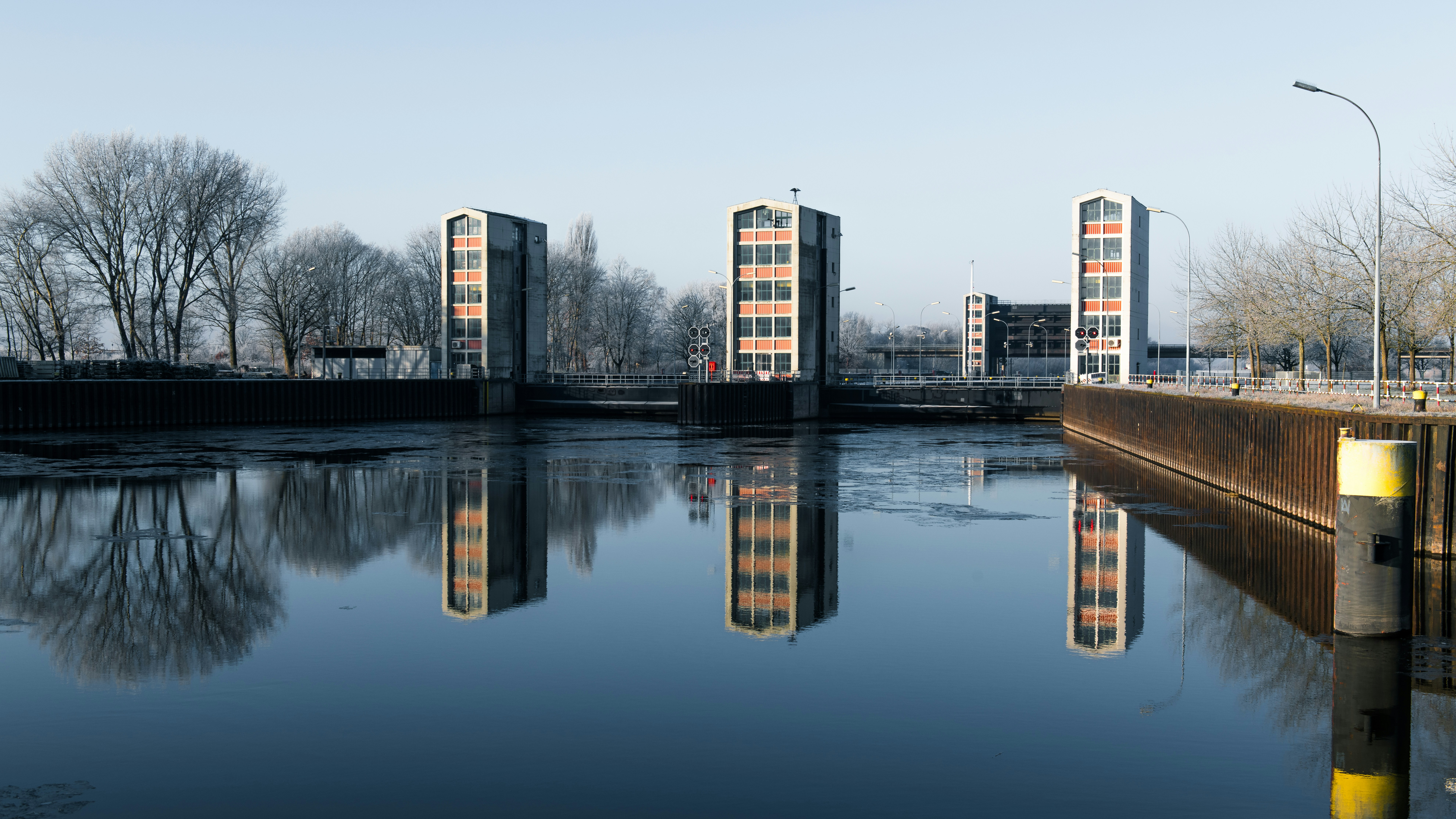 Modern buildings reflected in calm water on a clear day