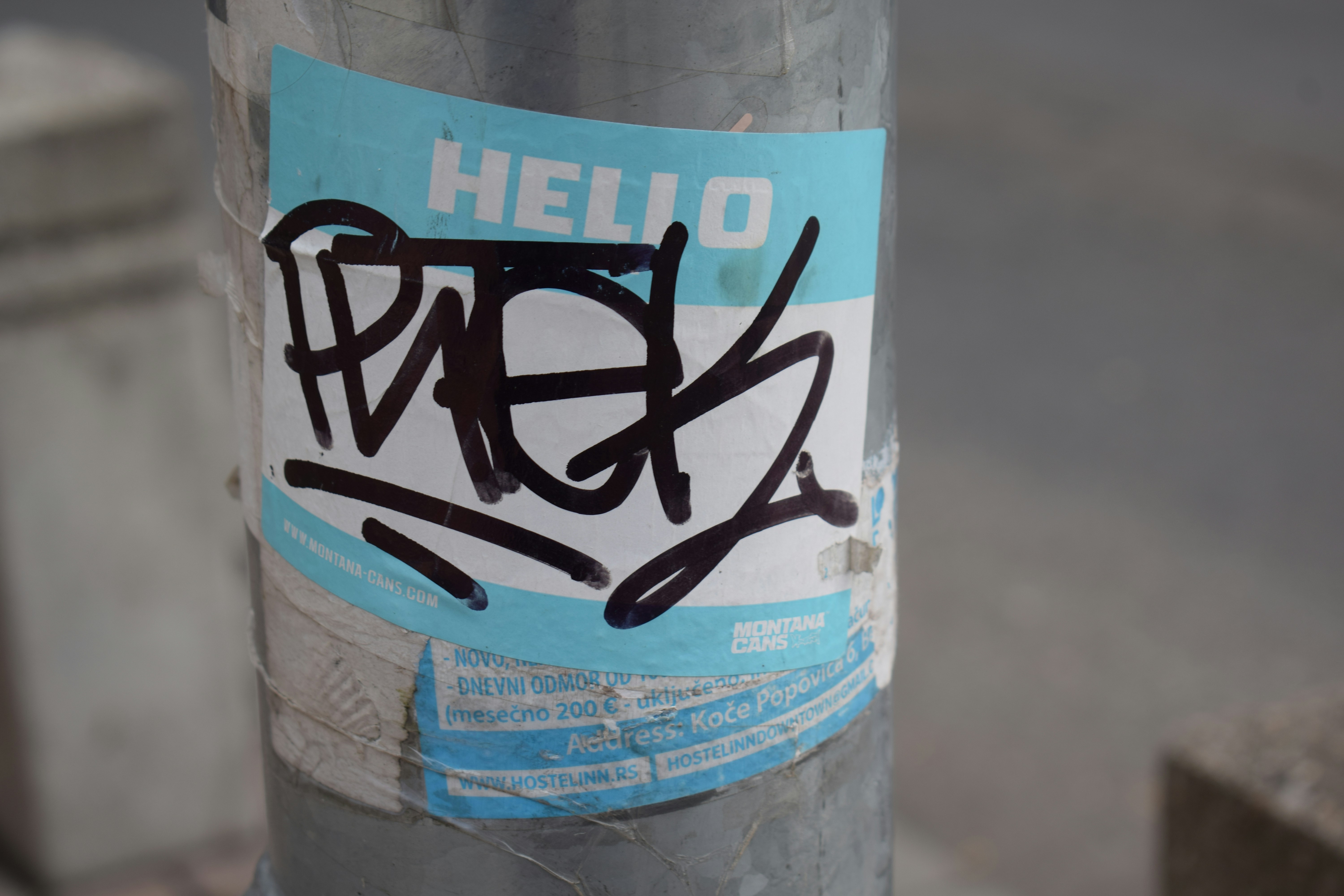 Hello sticker with black graffiti tag