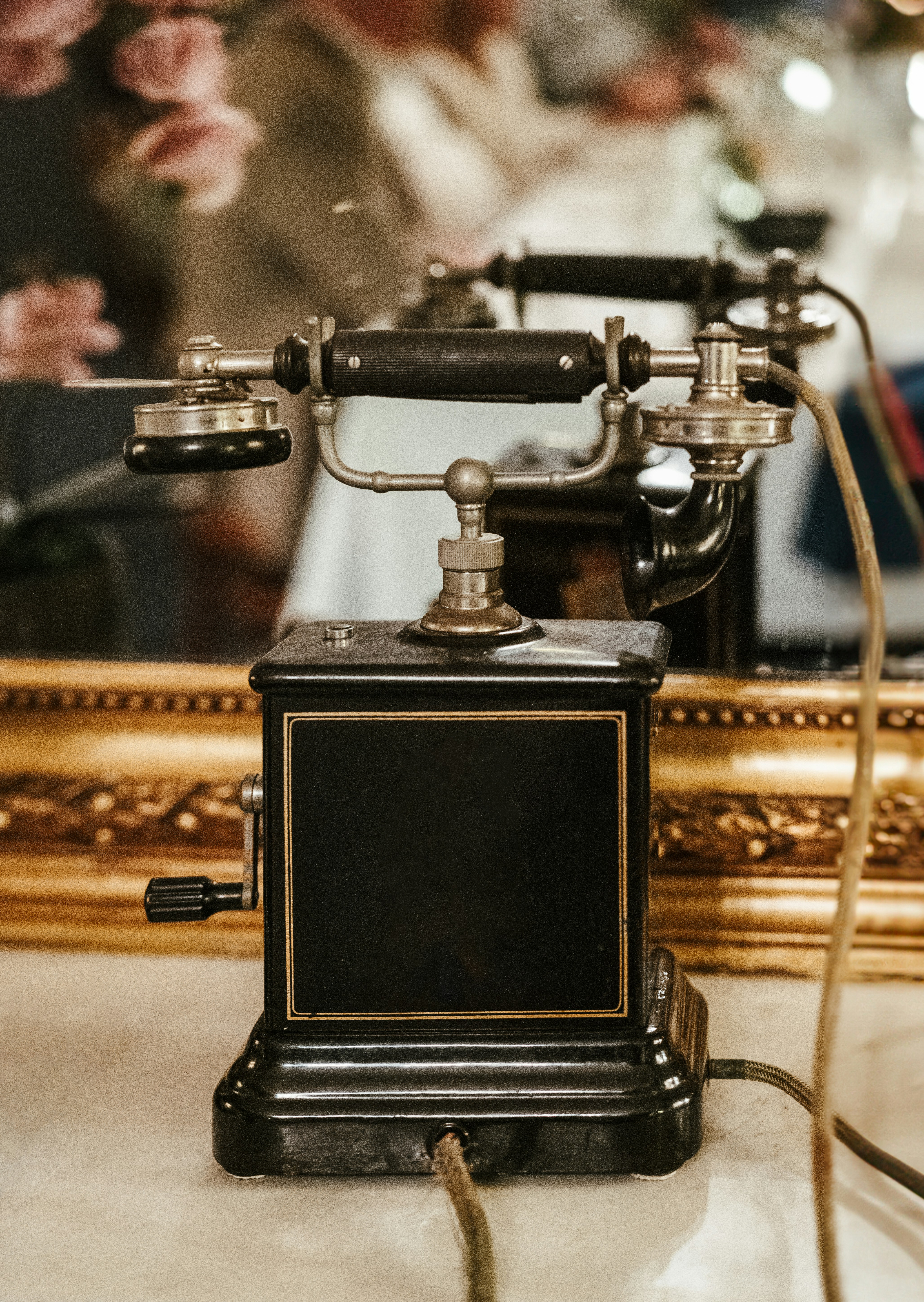 Antique black rotary telephone on a marble surface.