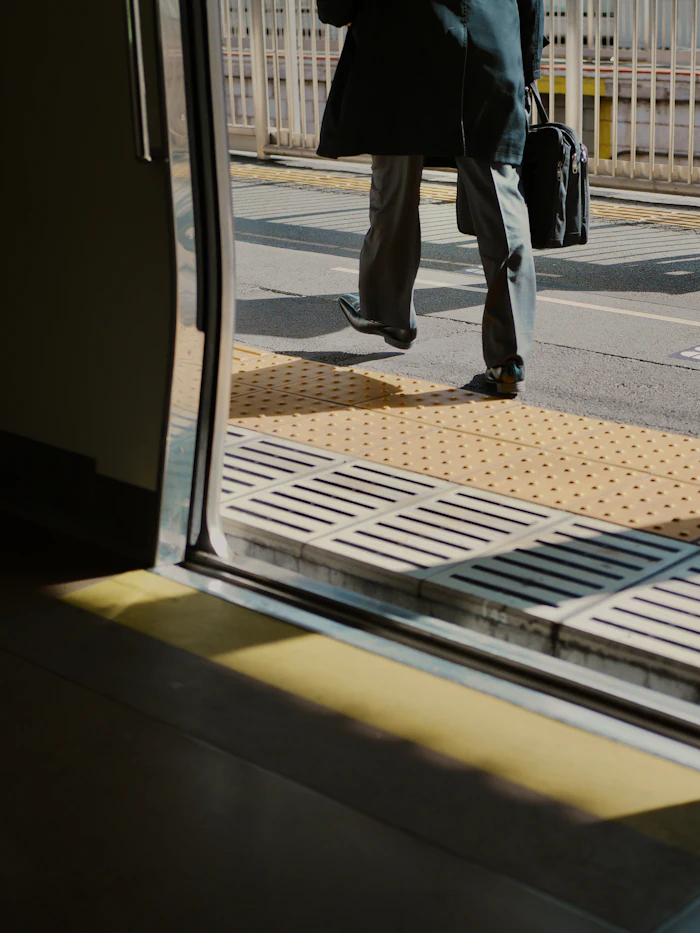 A traveller with a briefcase stepping from a train onto the platform