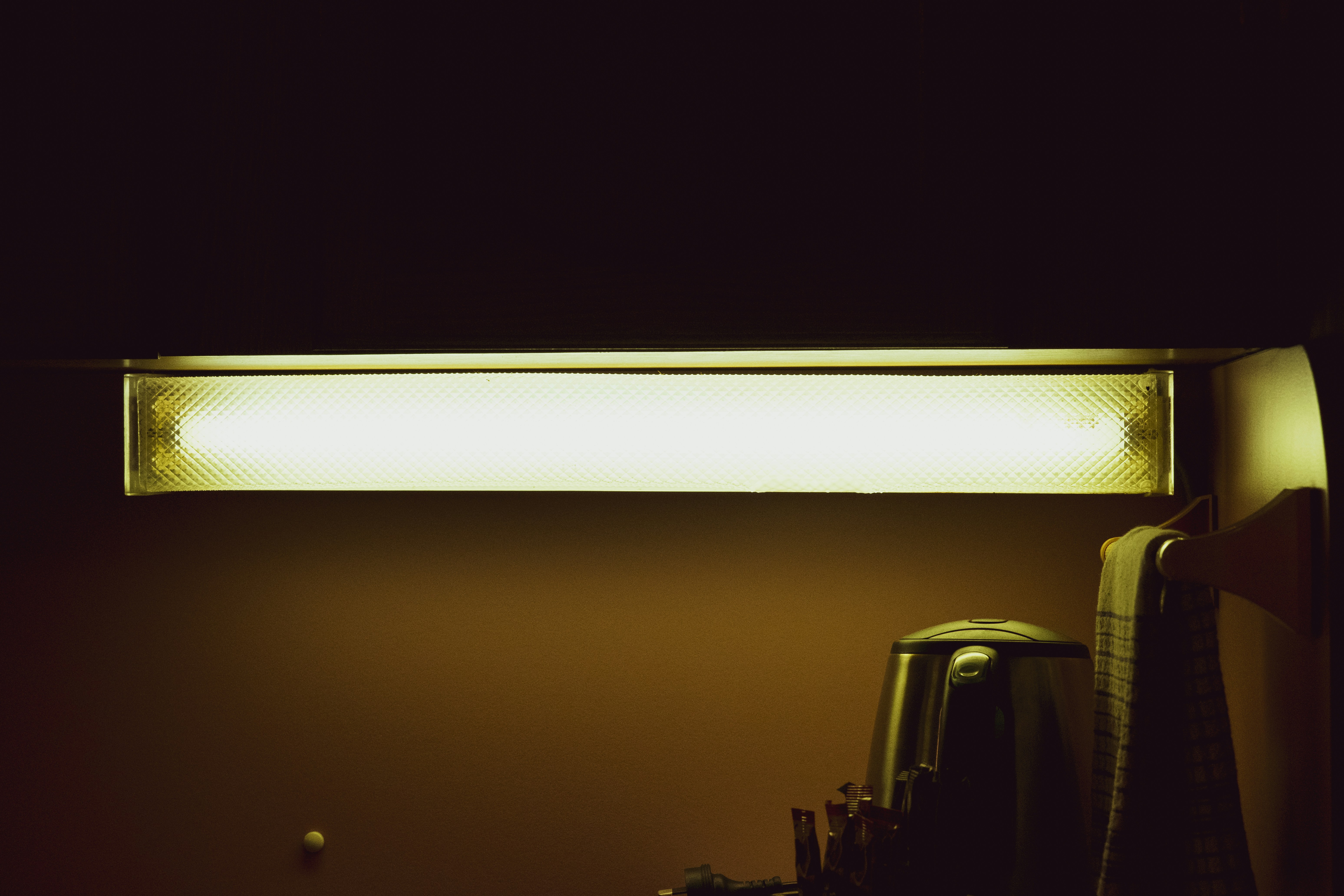 Fluorescent light fixture glowing in a dark room