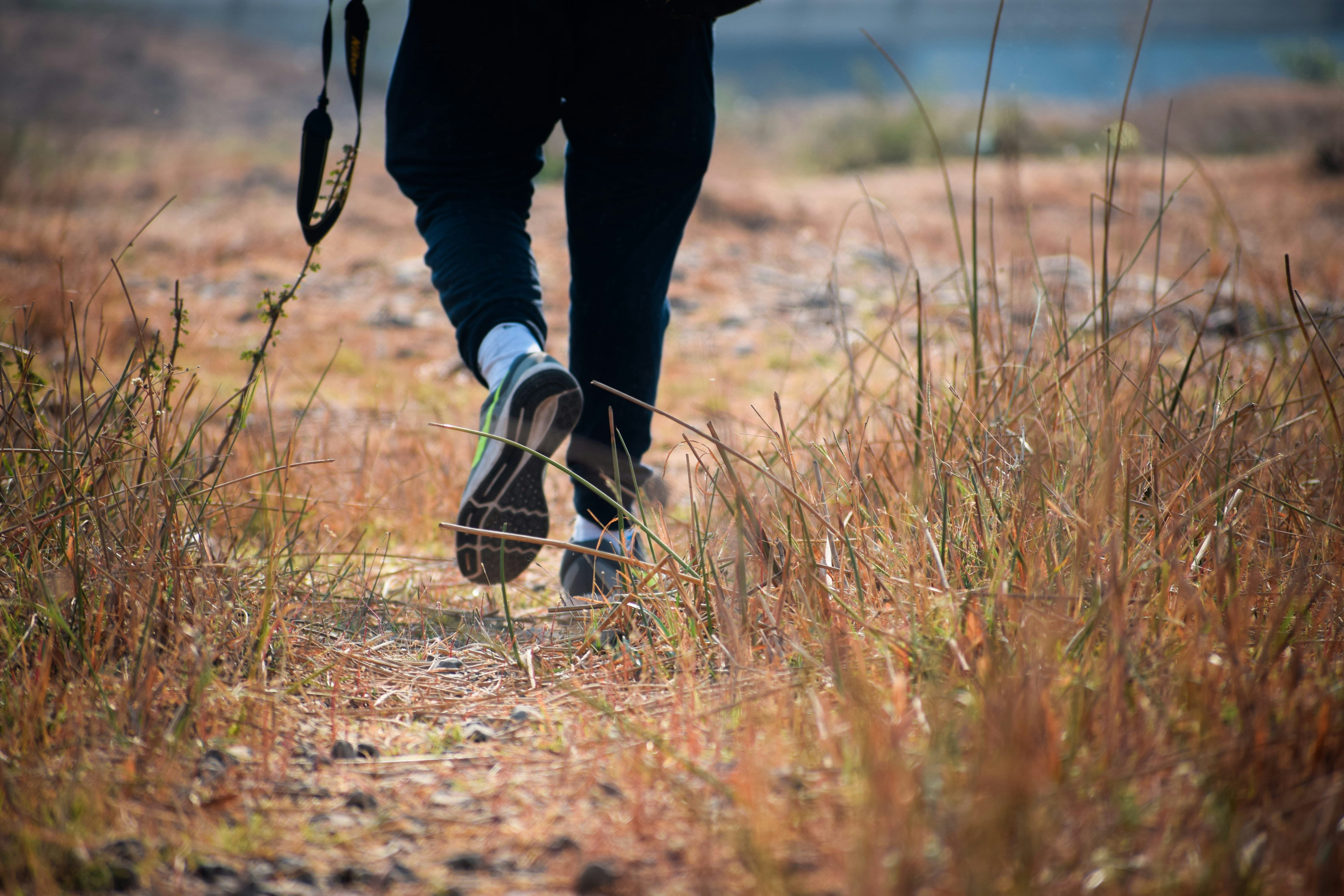 A person walking on a dry grassy path.