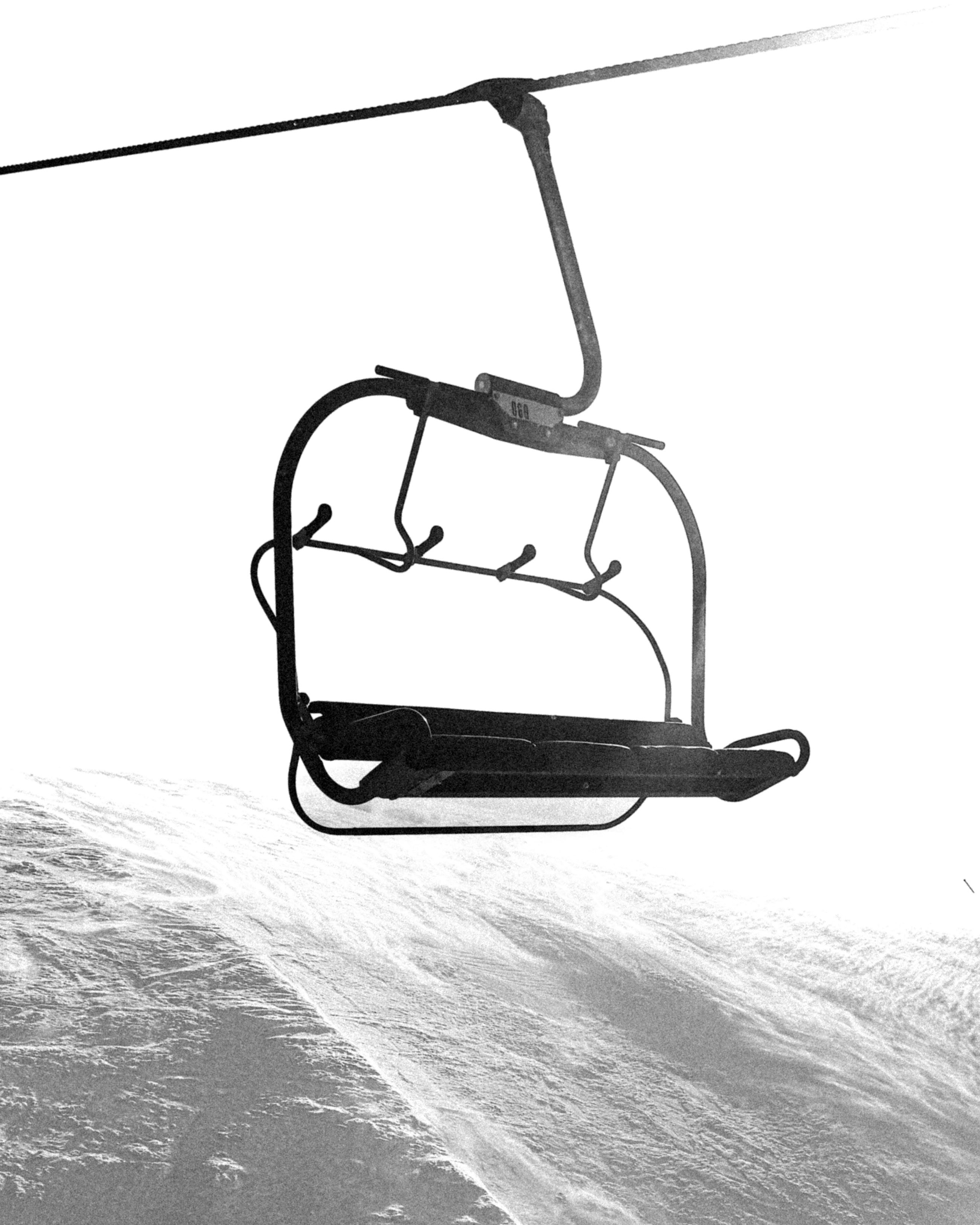 Empty ski lift chair against a snowy mountain