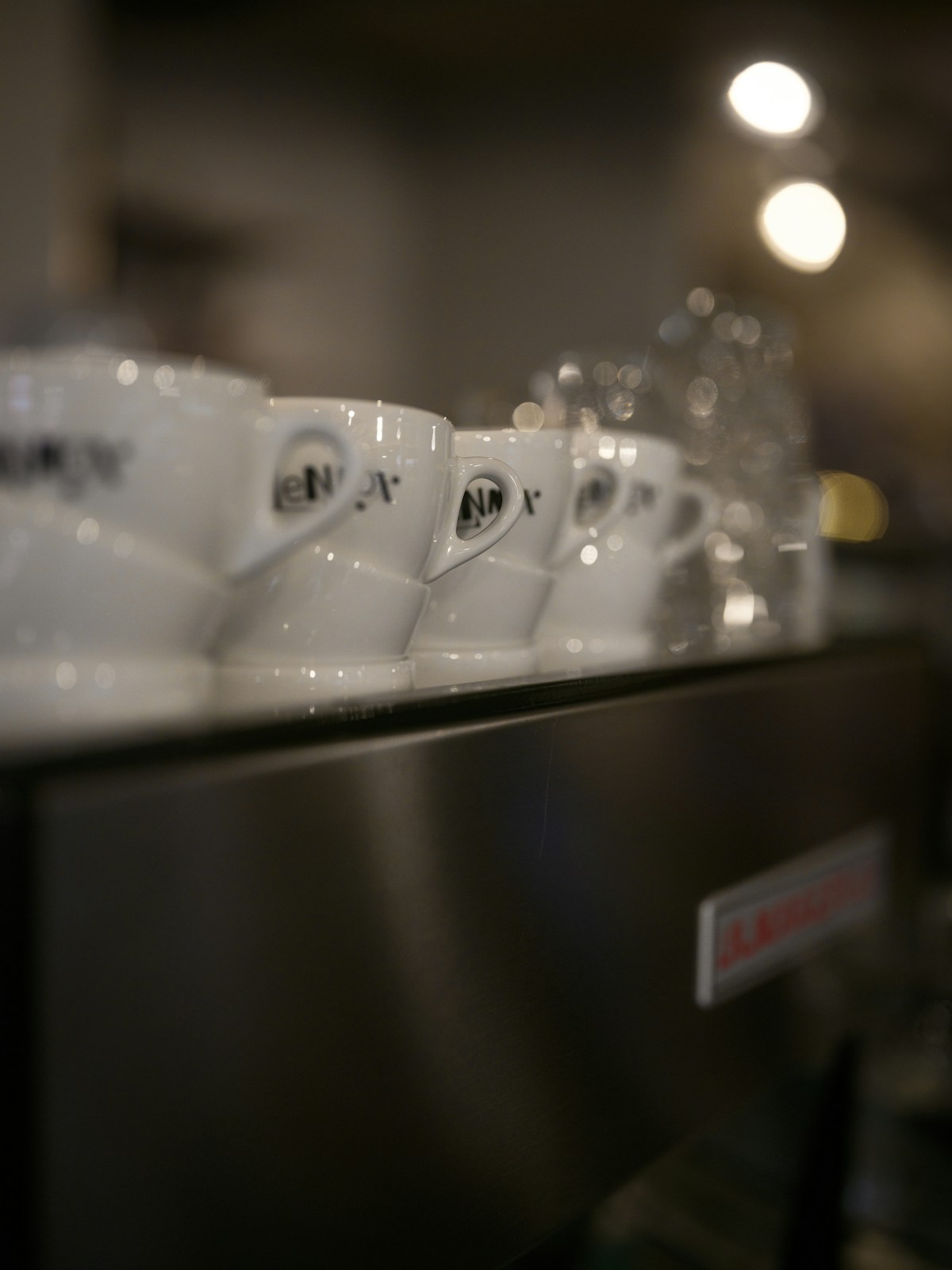 Rangée de tasses à expresso blanches posées sur le dessus d'une machine à café de bar
