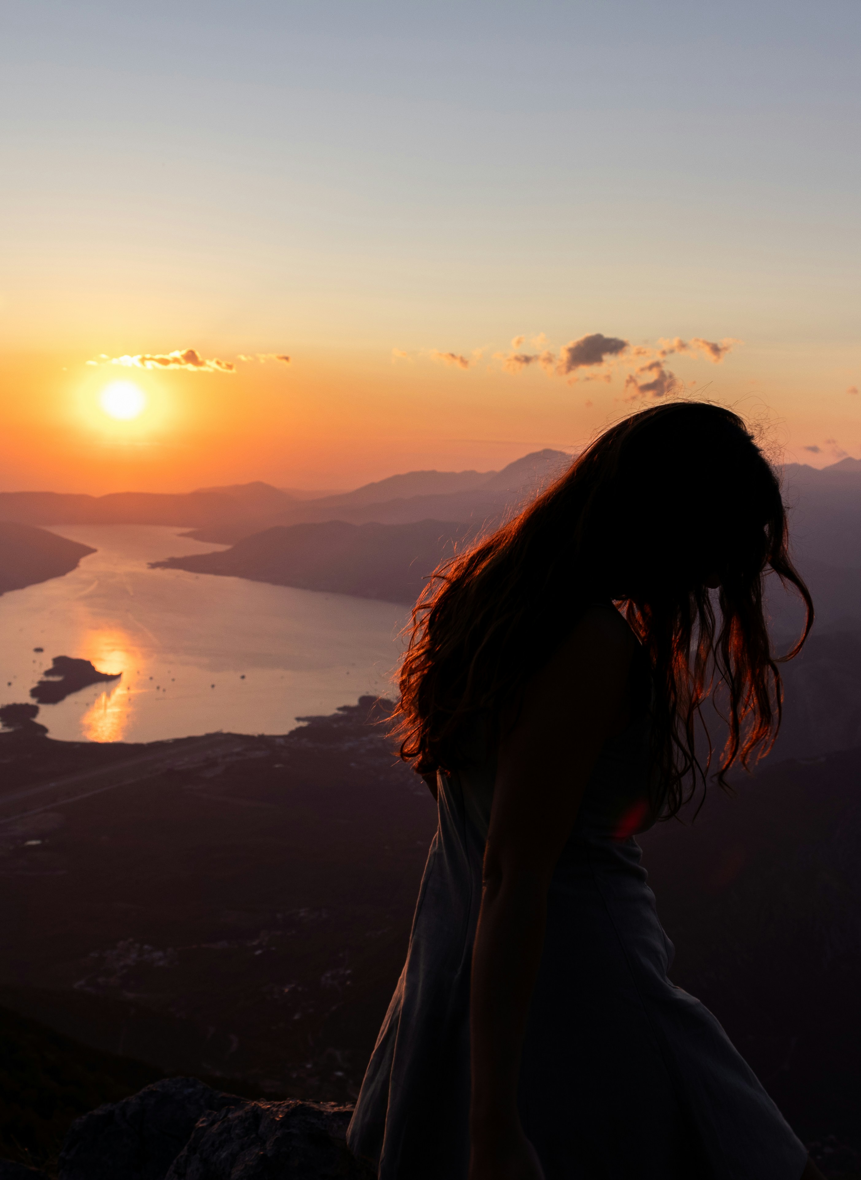 Silueto de una mujer contra un atardecer sobre el agua.