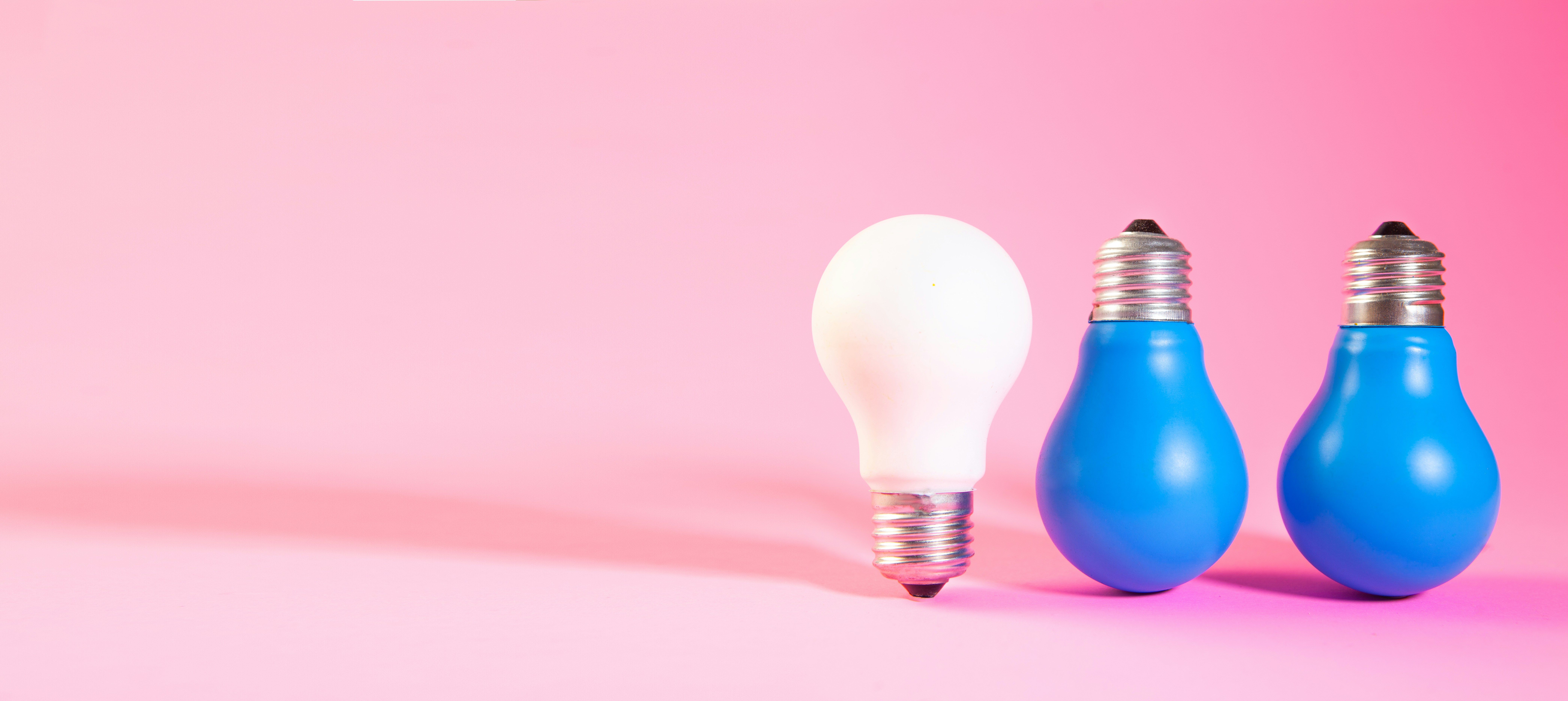 A white lightbulb stands out from two blue ones.