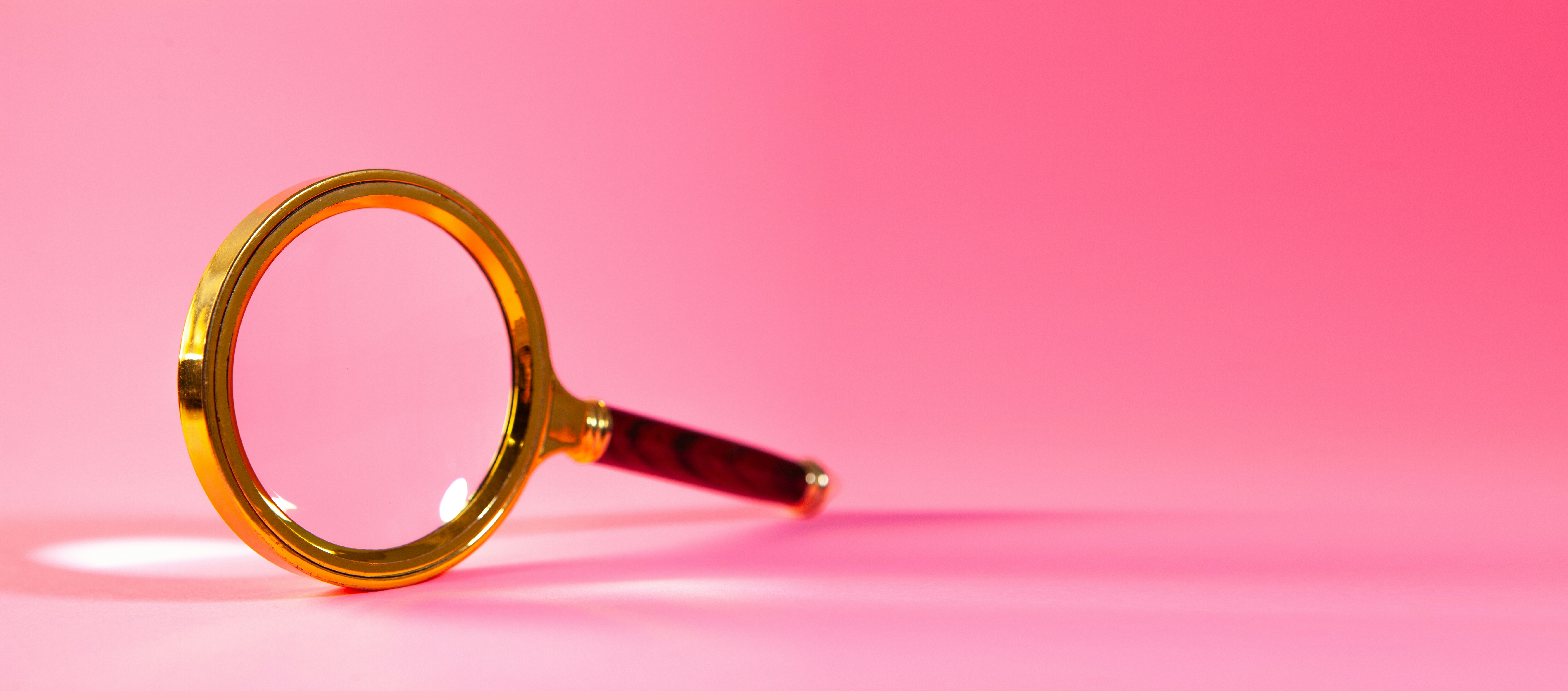 Magnifying glass on pink background.