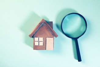 Magnifying glass over a wooden house model.