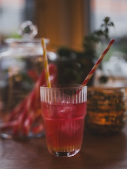 A red cocktail with two straws in a glass.