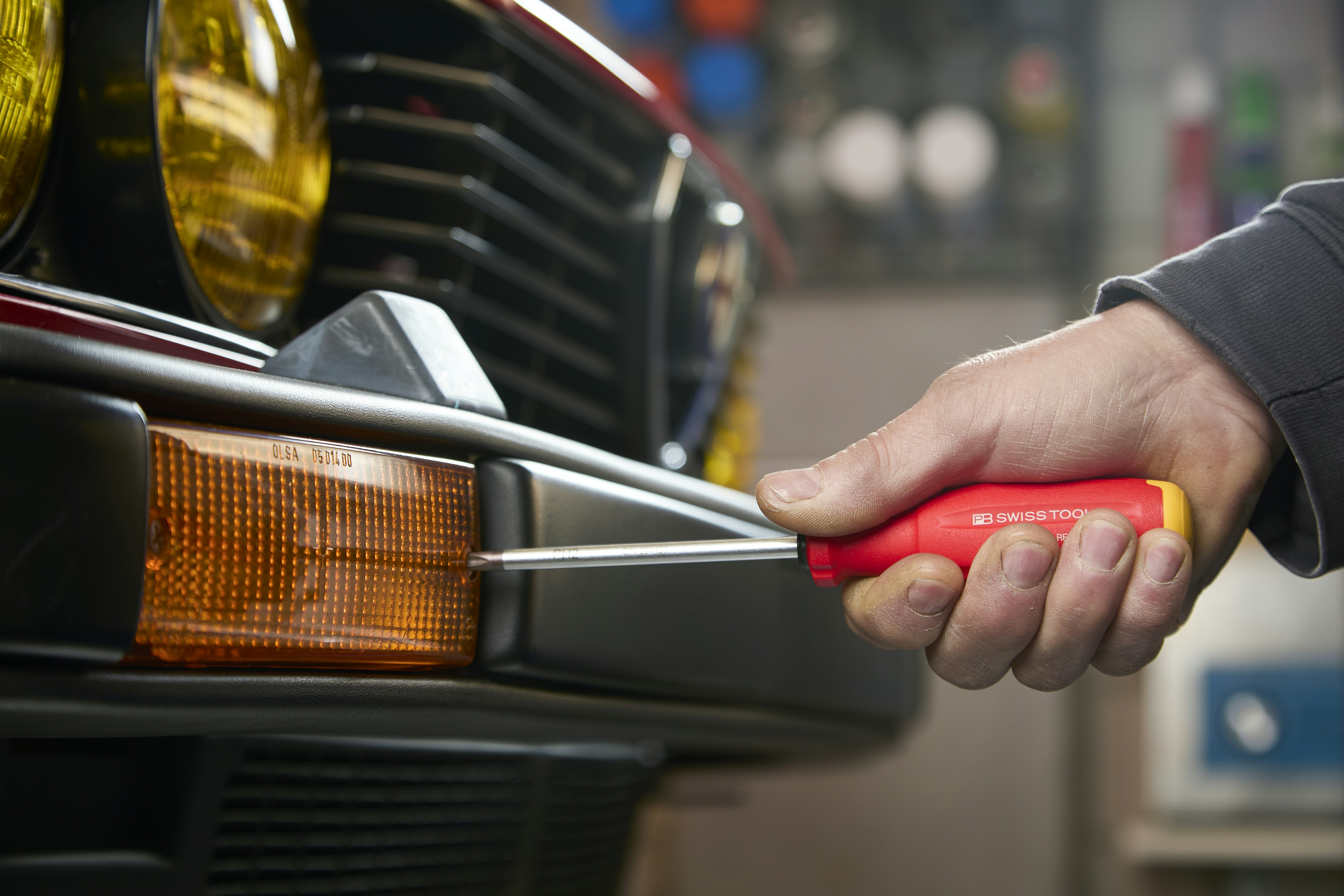 Hand using screwdriver to fix car bumper