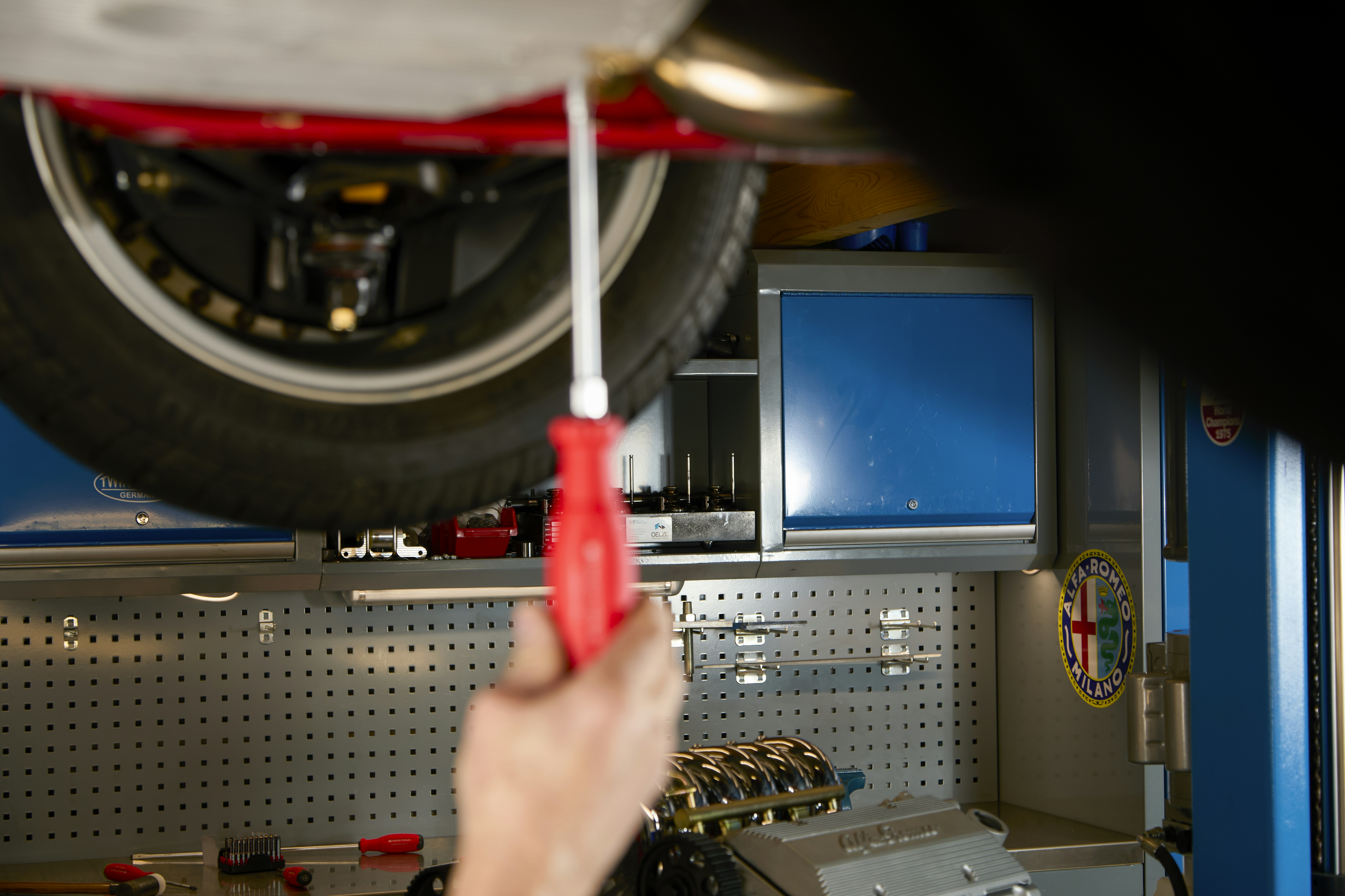 Mechanic using screwdriver on car part
