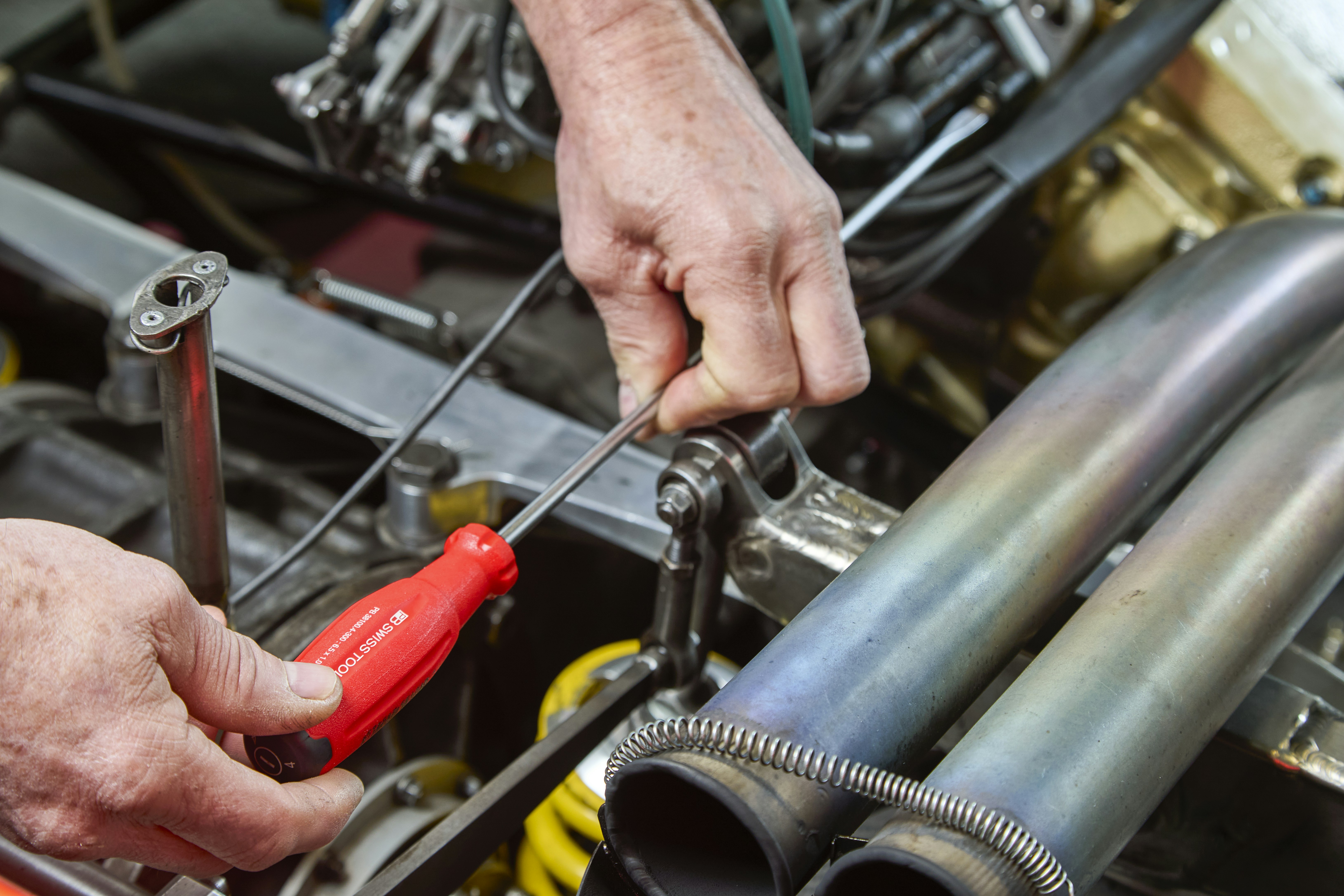 Mechanic working on car engine with tools.