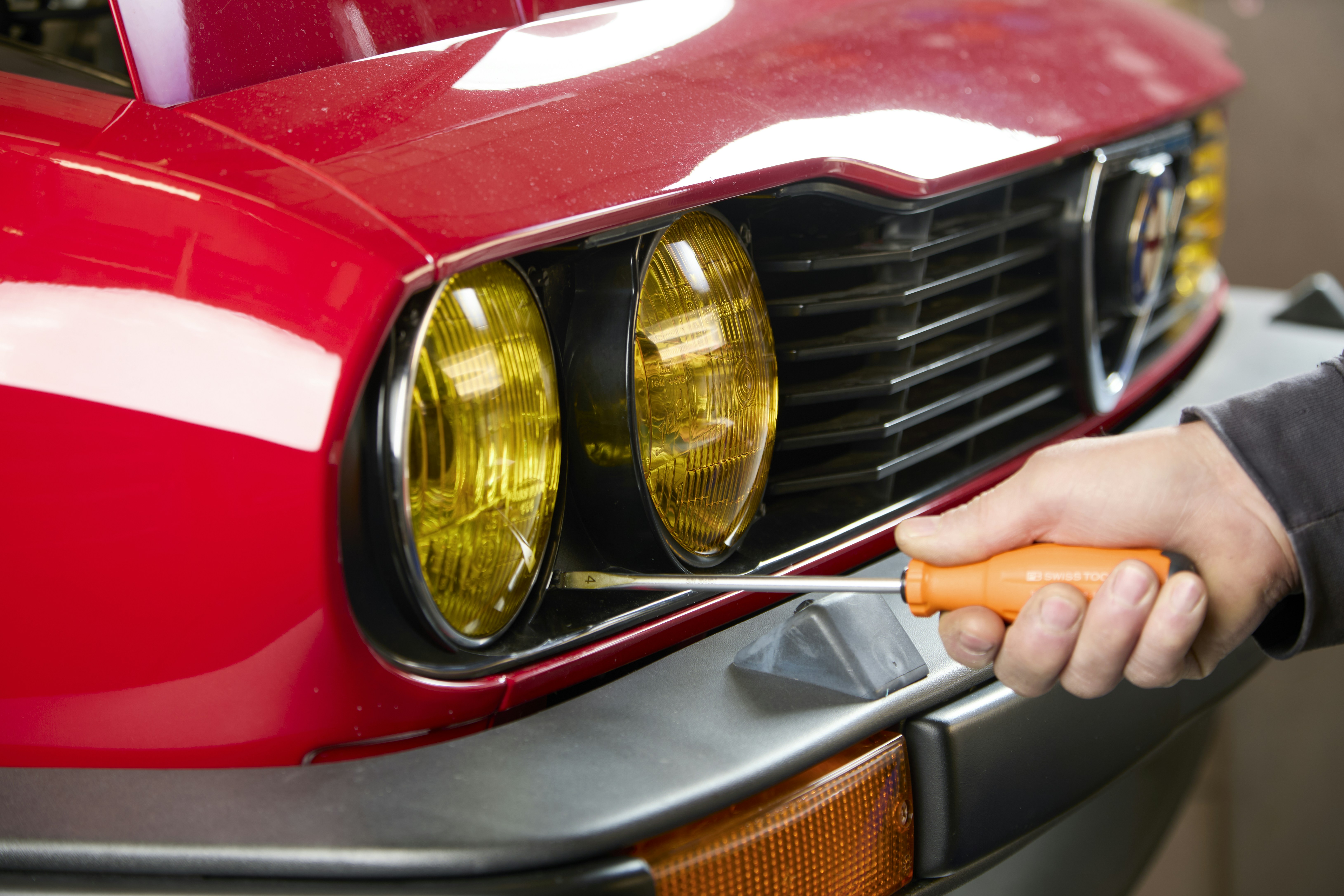 Hand using screwdriver on car headlight