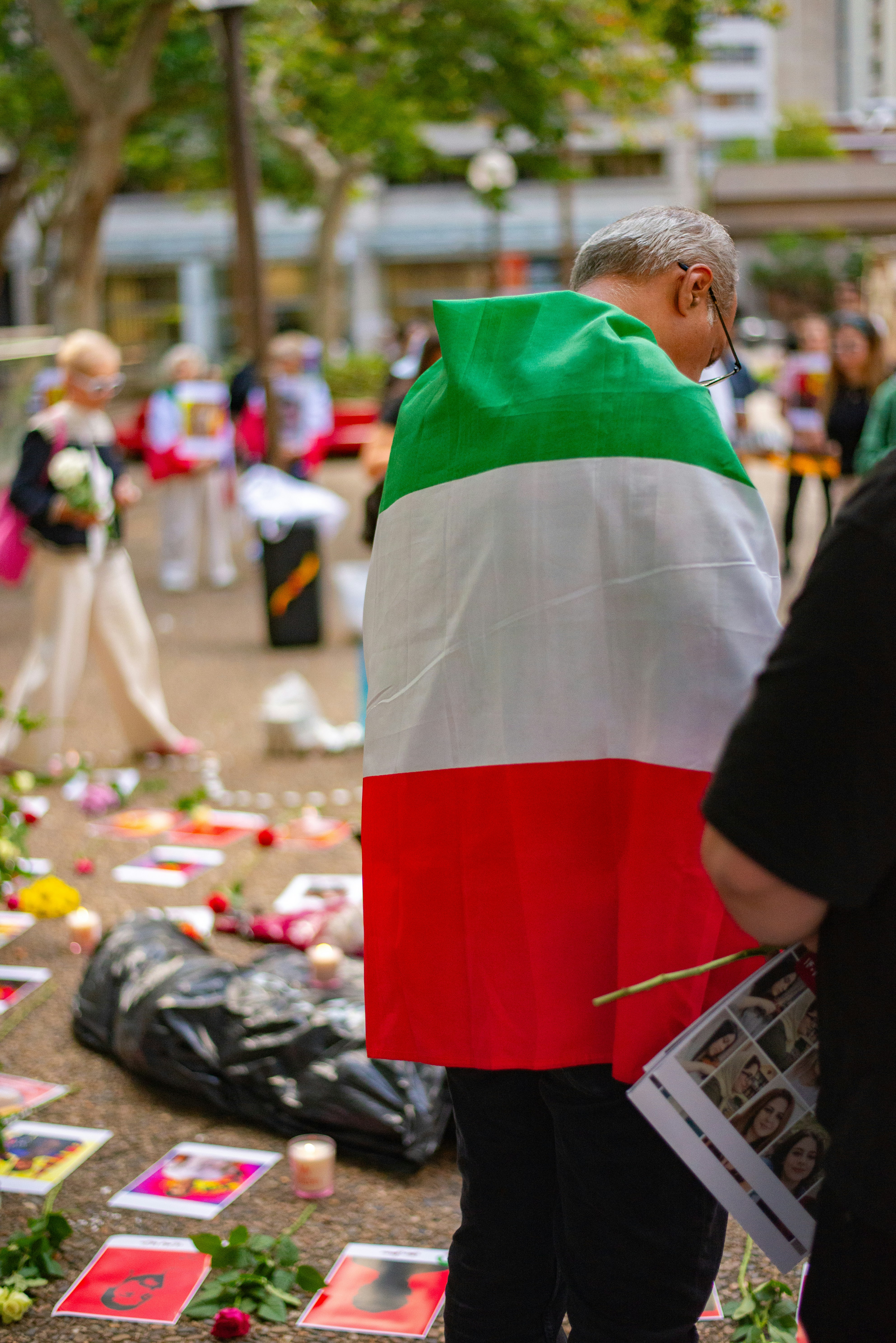 Man draped in italian flag at memorial with photos