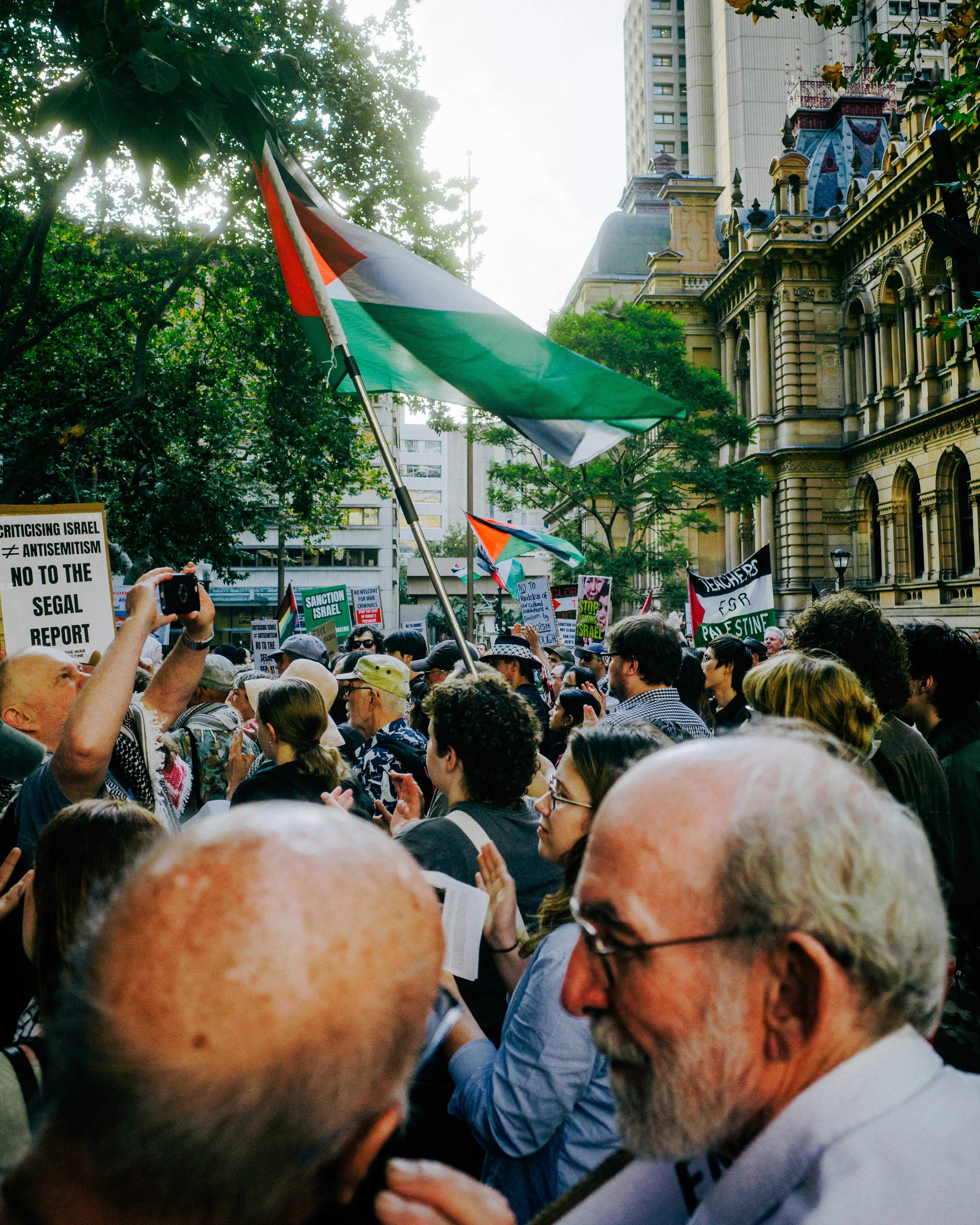 People protest with palestinian flags in a city.