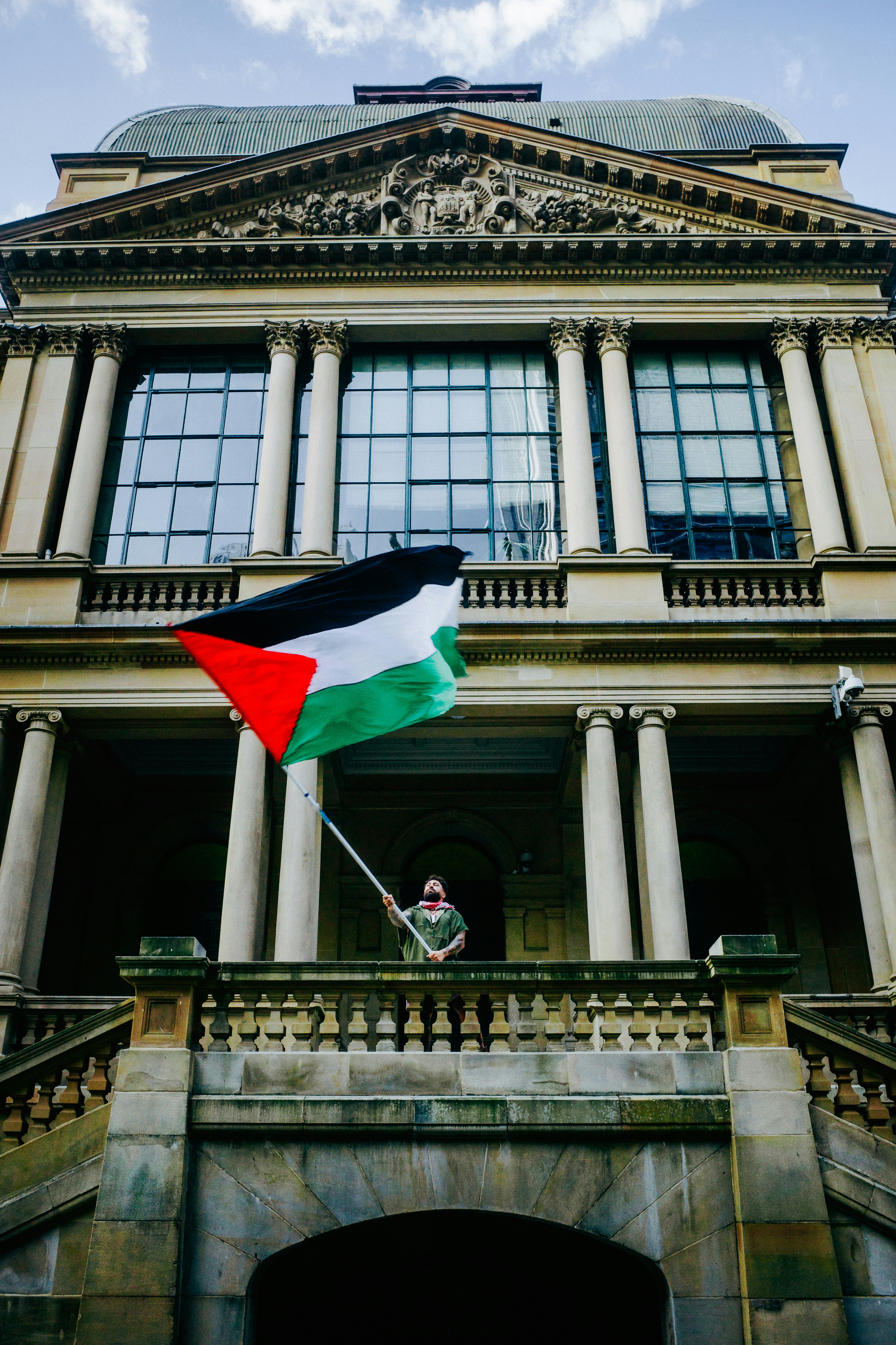 Person holding palestinian flag on building balcony