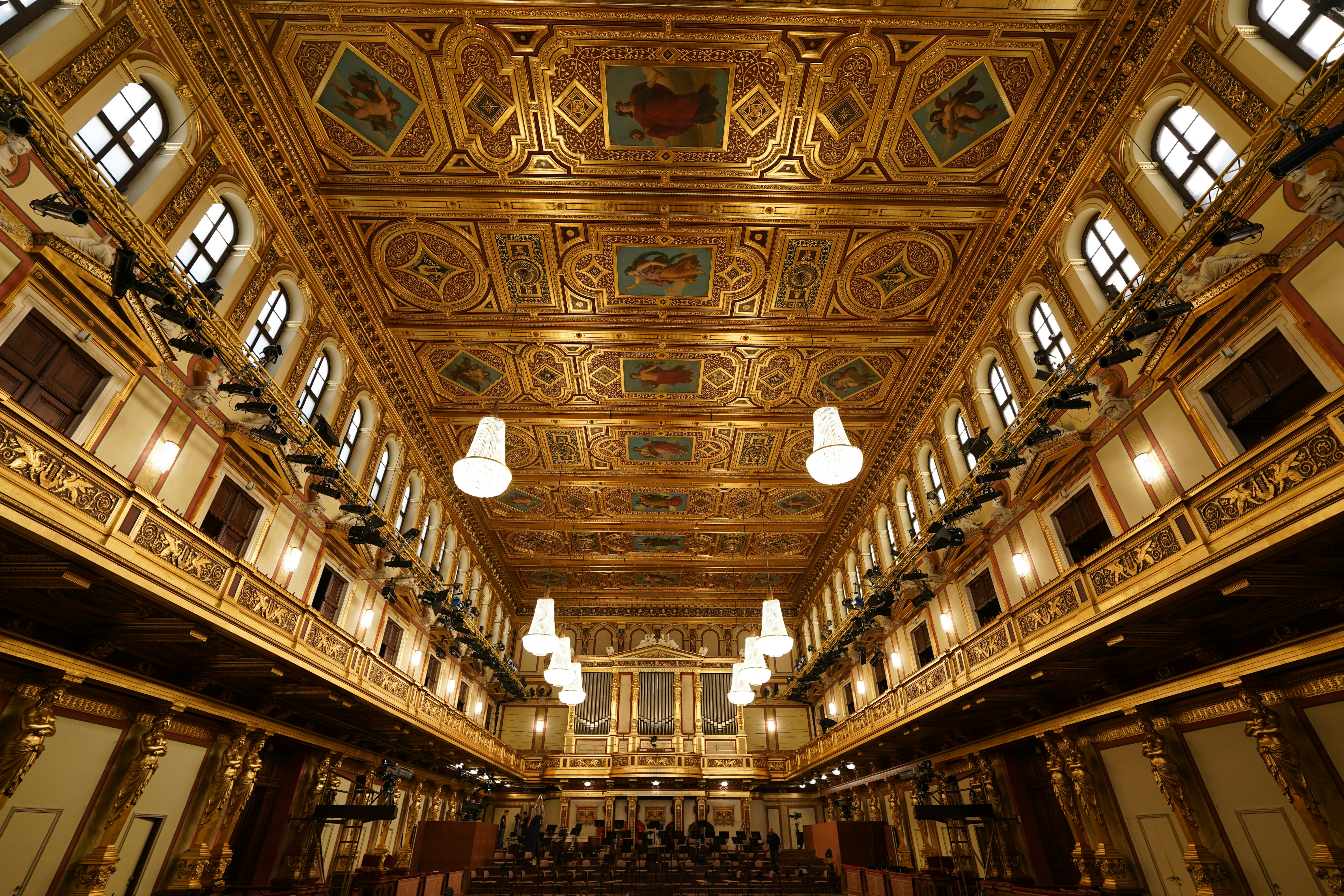 Ornate golden concert hall with chandeliers and audience