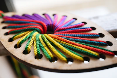 Colorful ropes threaded through wooden shape