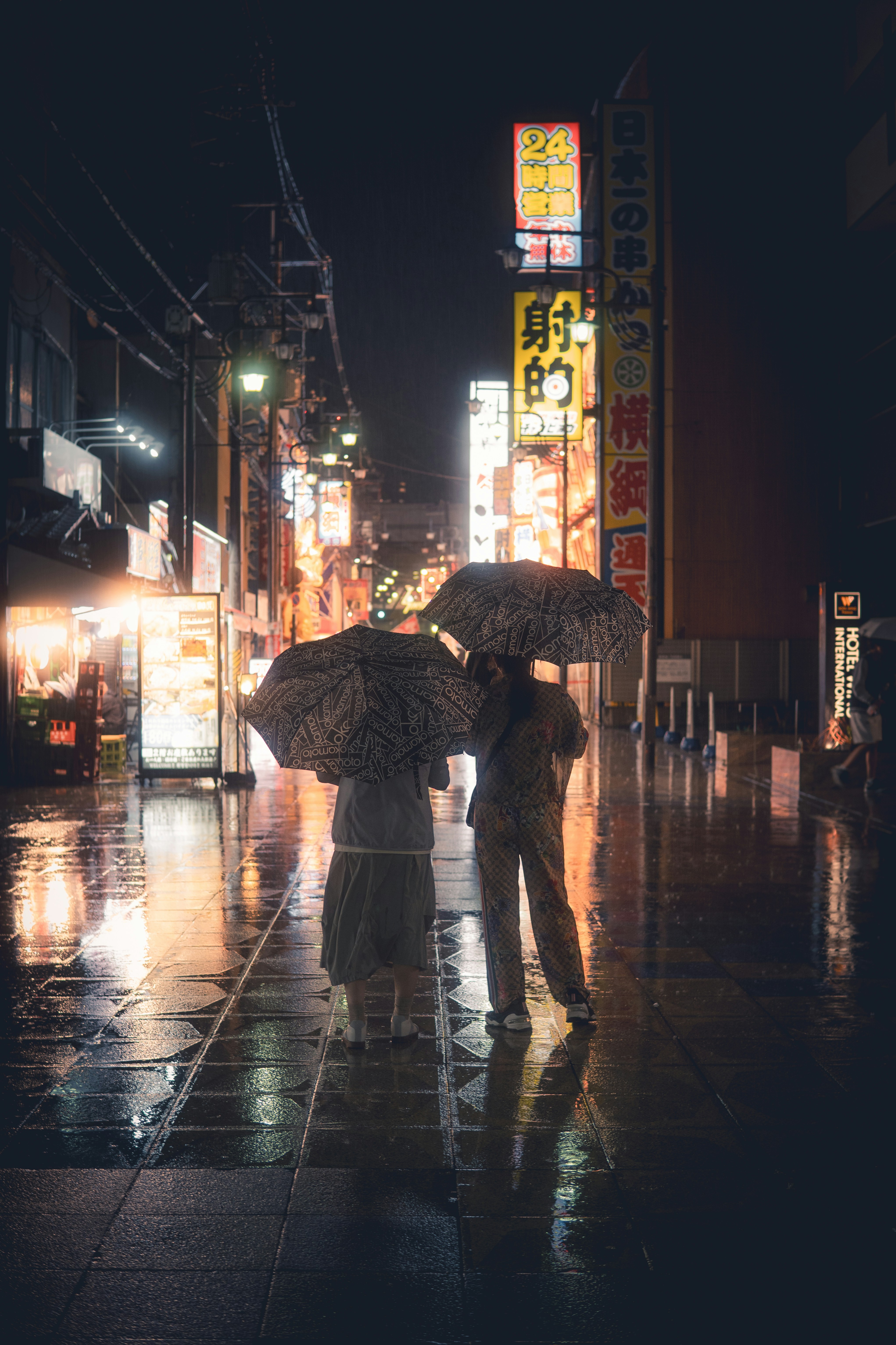Two people walk with umbrellas on a rainy city street.